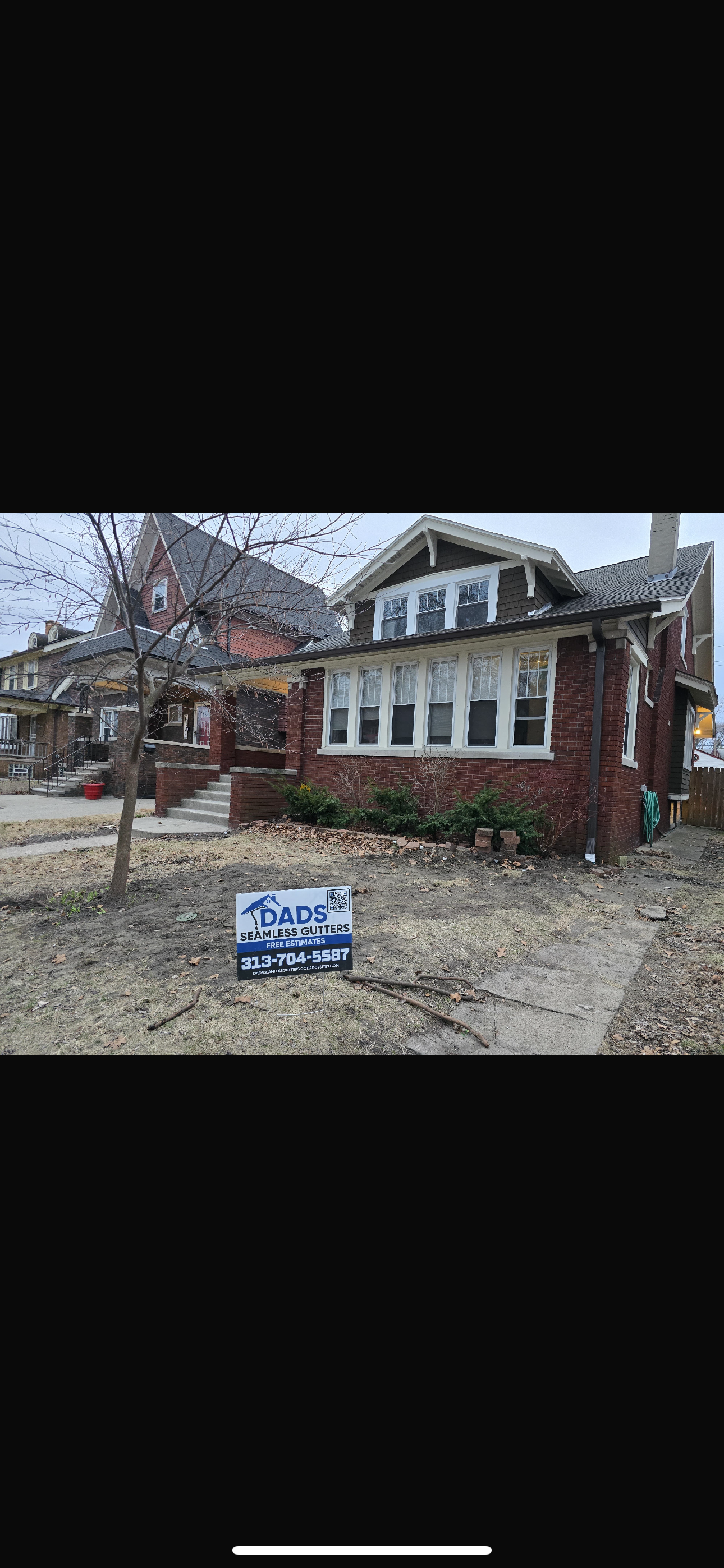 Front view of a brick house with a sign in the yard advertising seamless gutter services from DADS seamless gutters with contact information and a QR code. 3137045587 michigan