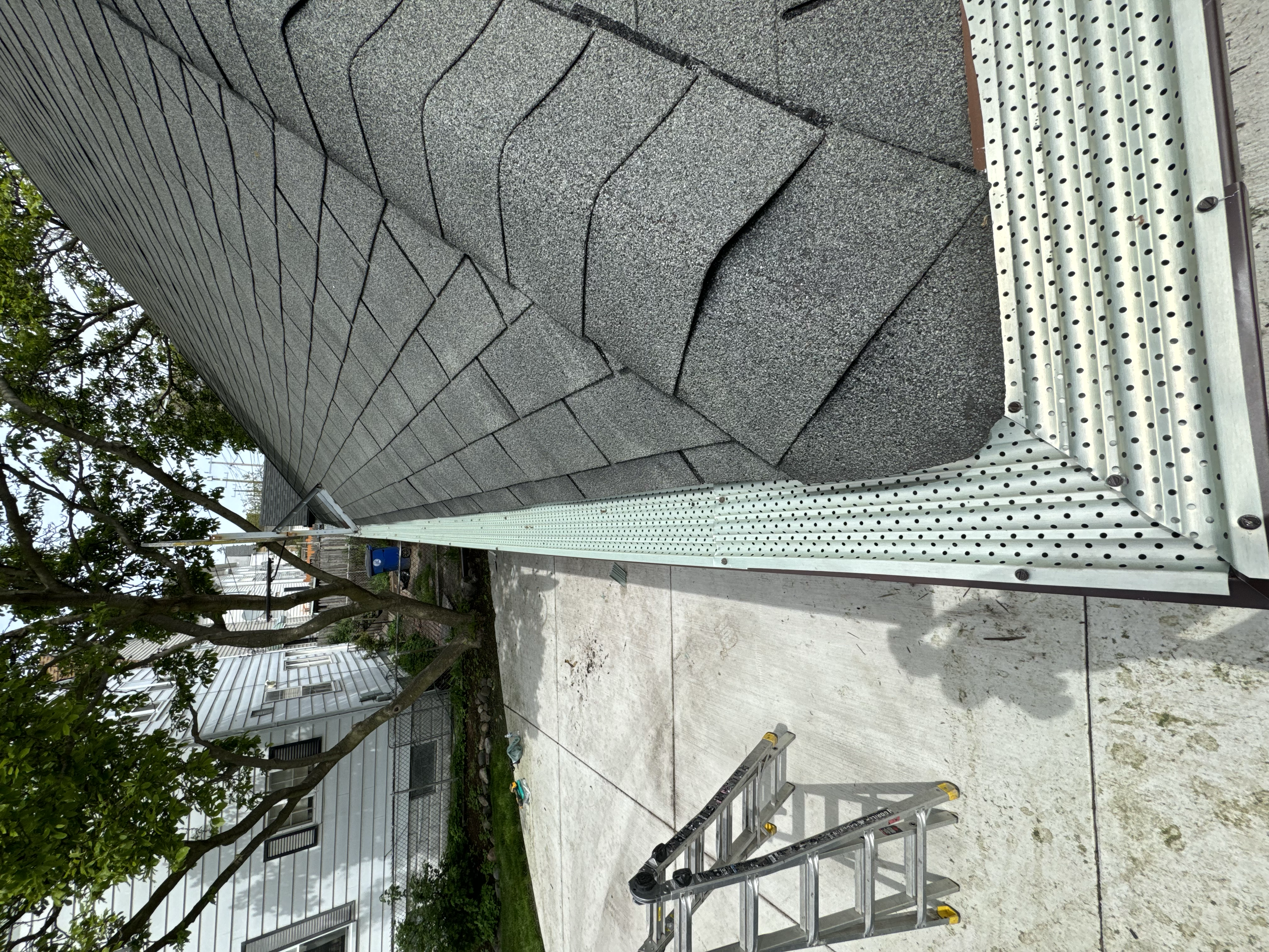 Exterior wall of a building with grey shingles, a gutter, and a gutter guards installed by dads seamless gutters in Bloomfield Hills,michigan