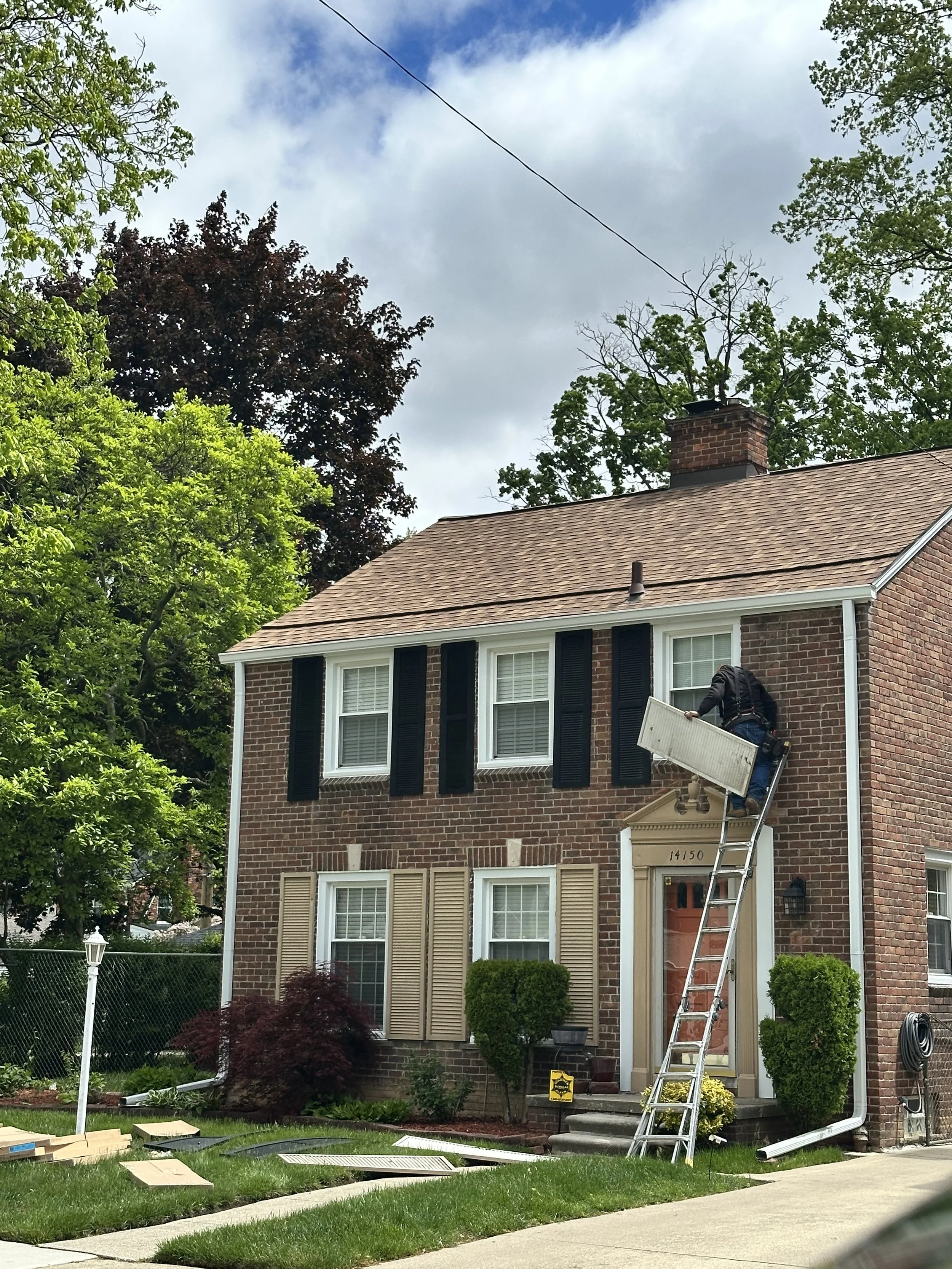 A dads seamless gutter installer on a ladder installing seamless gutters white in northville Michigan 