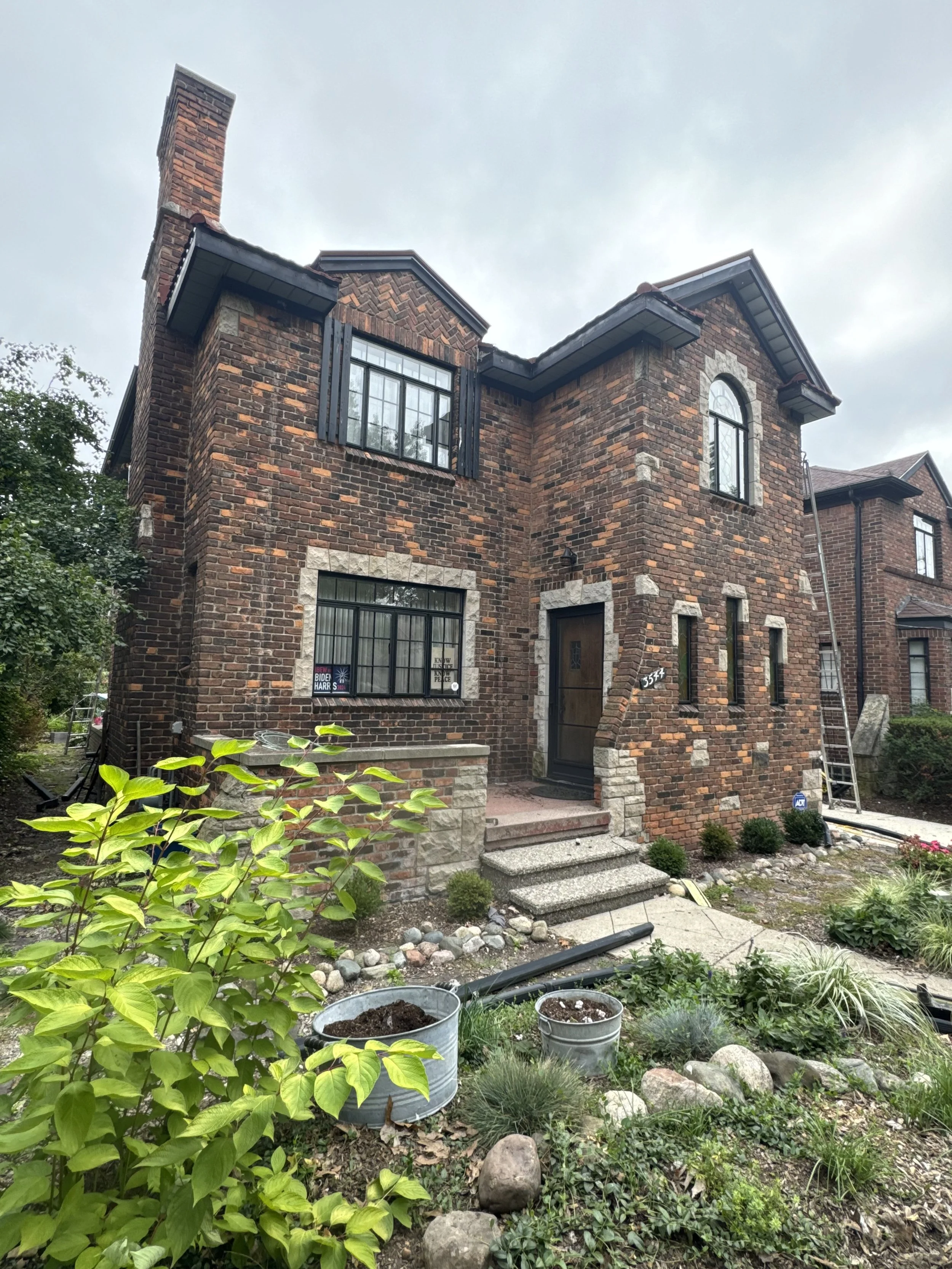 A two-story brick house with dark window trim, and seamless black gutters installed by dads seamless gutter k-style gutters and 5' gutters black gutters 6' gutters seamless gutter in michigan