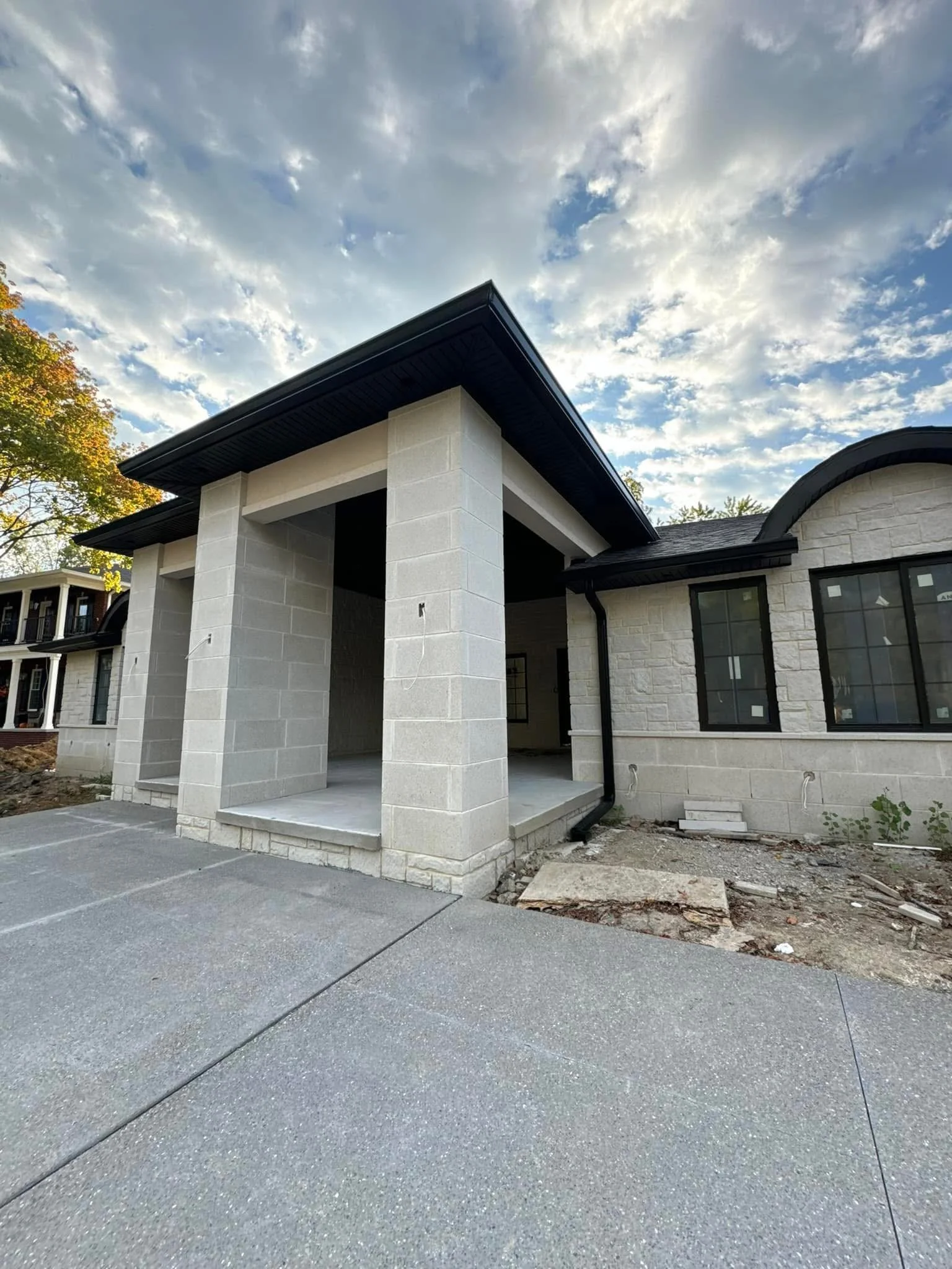 Newly constructed house with a stone facade, large windows, black seamless half round gutters installed by dads seamless gutters in Dearborn michigan