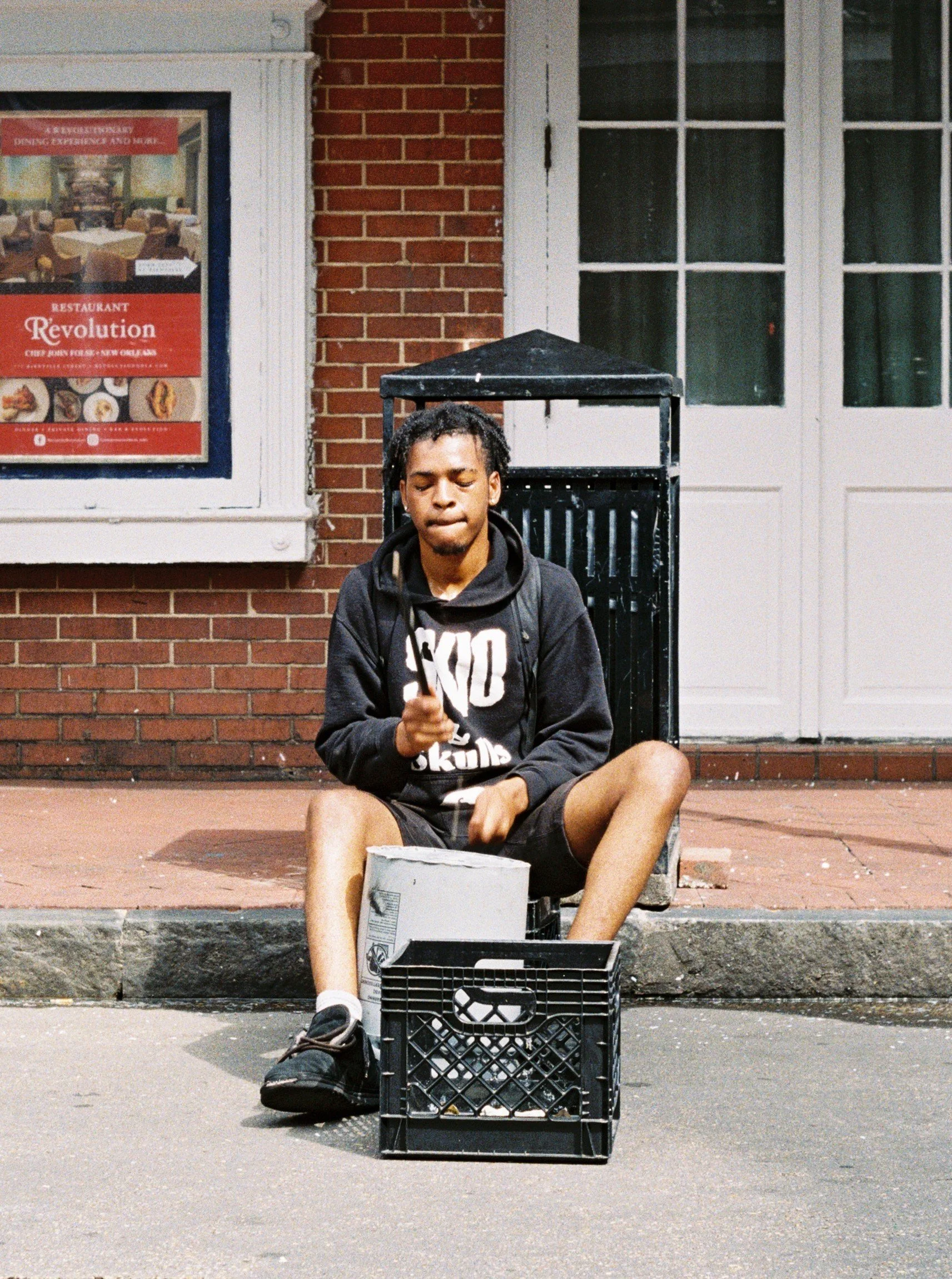 Street performer playing a drum, but it's a bucket on Bourbon St in New Orleans, Louisiana.