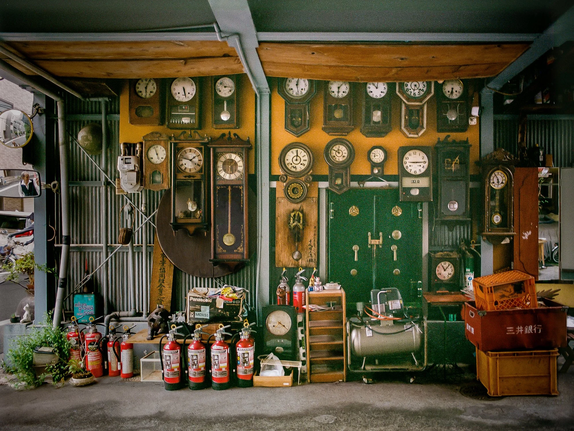 Curious display of antique wall clocks, fire extinguishers and a safe in a carport in Tokyo, Japan.