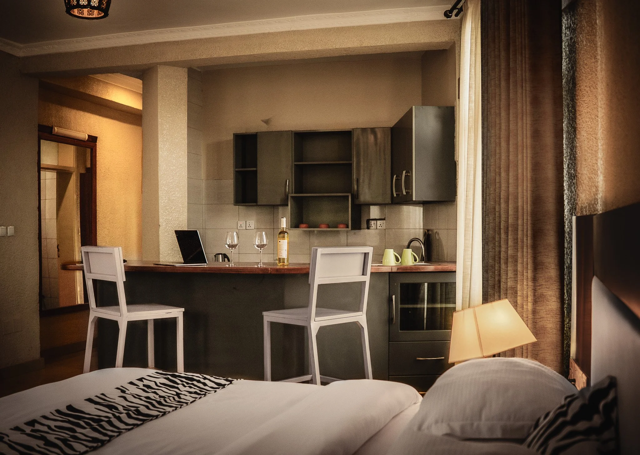 King Studio at Quality Inn Hotel Kigali, Rwanda: cozy super king bed, zebra-print runner, kitchenette, bar with wine & stools—perfect for couples & friends traveling in Rwanda seeking a comfortable and stylish stay.