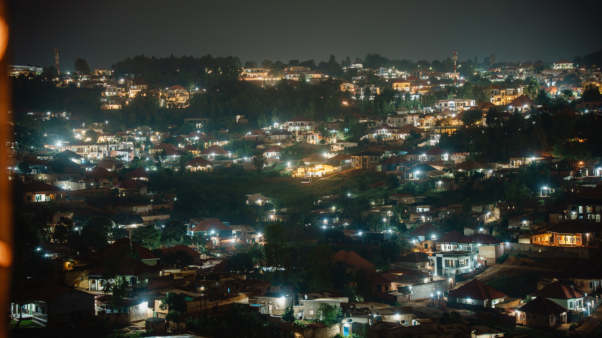 Nighttime view of a quiet residential neighborhood in Kigali with softly lit houses on hilly terrain, peaceful surroundings near Quality Inn Hotel Kigali, Rwanda