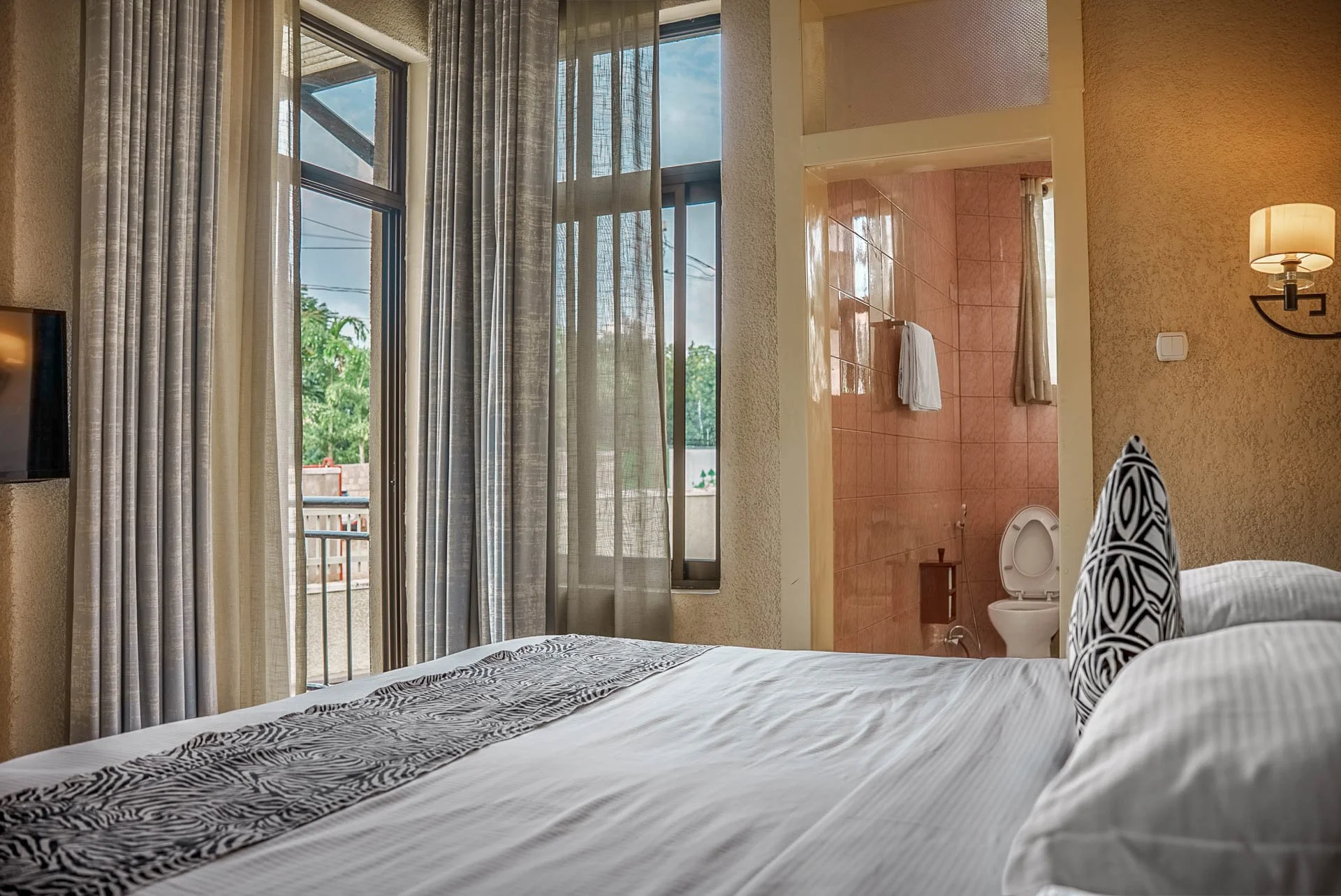 Private and quiet hotel room at Quality Inn Hotel Kigali in Rwanda, featuring large windows, balcony access, and a private bathroom—ideal for couples, families, and business travelers, a peaceful hideout.