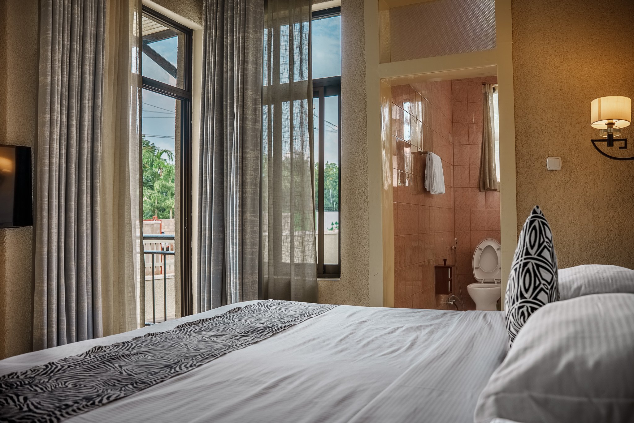 Private and quiet hotel room at Quality Inn Hotel Kigali in Rwanda, featuring large windows, balcony access, and a private bathroom—ideal for couples, families, and business travelers, a peaceful hideout.