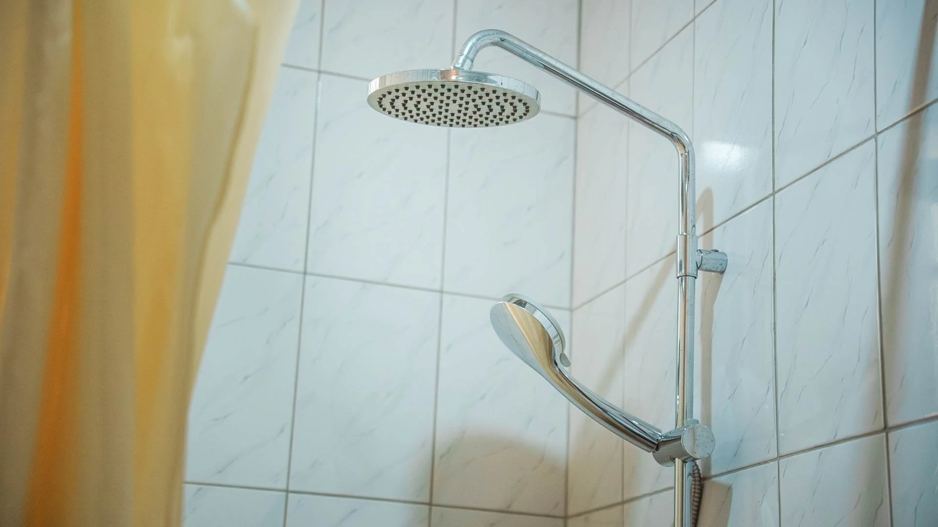 Showerhead and handheld shower in a tiled bathroom shower area at Quality Inn Hotel Kigali, Rwanda
