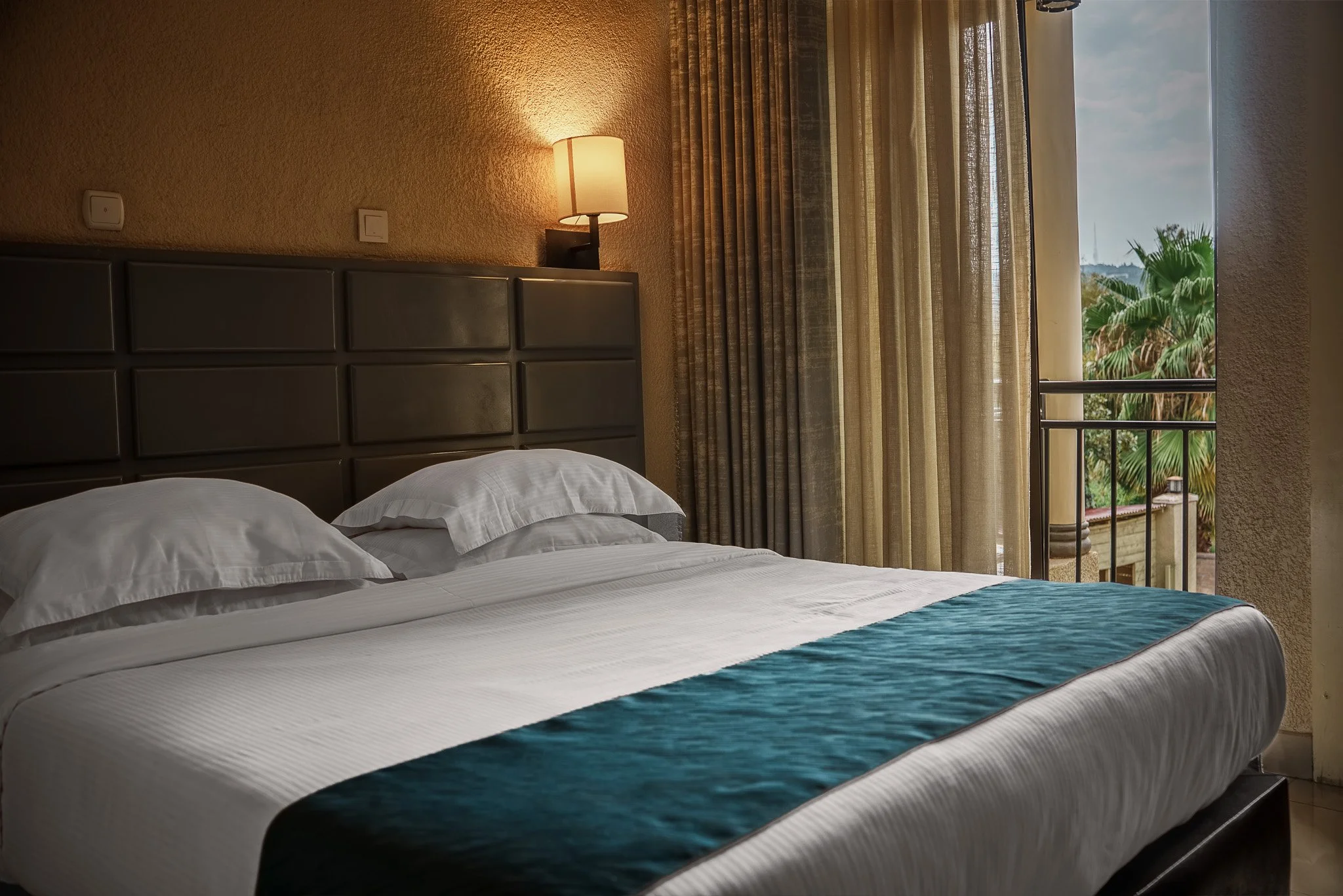 Comfortable hotel room at Quality Inn Hotel Kigali in Rwanda with a cozy bed, fresh linens, warm lighting, and private balcony—ideal for couples, friends, families, and business travelers, a quiet hideaway.