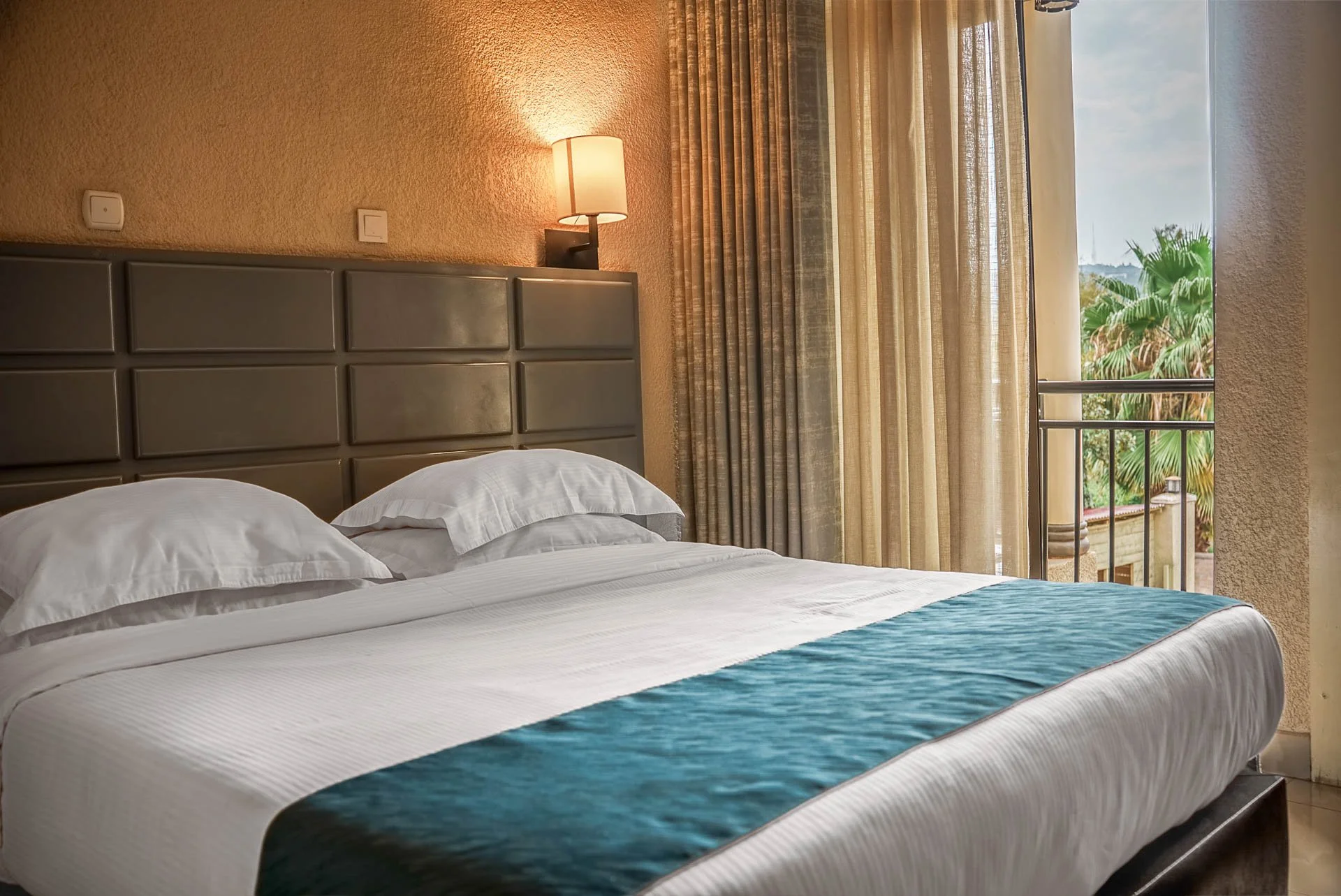 Comfortable hotel room at Quality Inn Hotel Kigali in Rwanda with a cozy bed, fresh linens, warm lighting, and private balcony—ideal for couples, friends, families, and business travelers, a quiet hideaway.