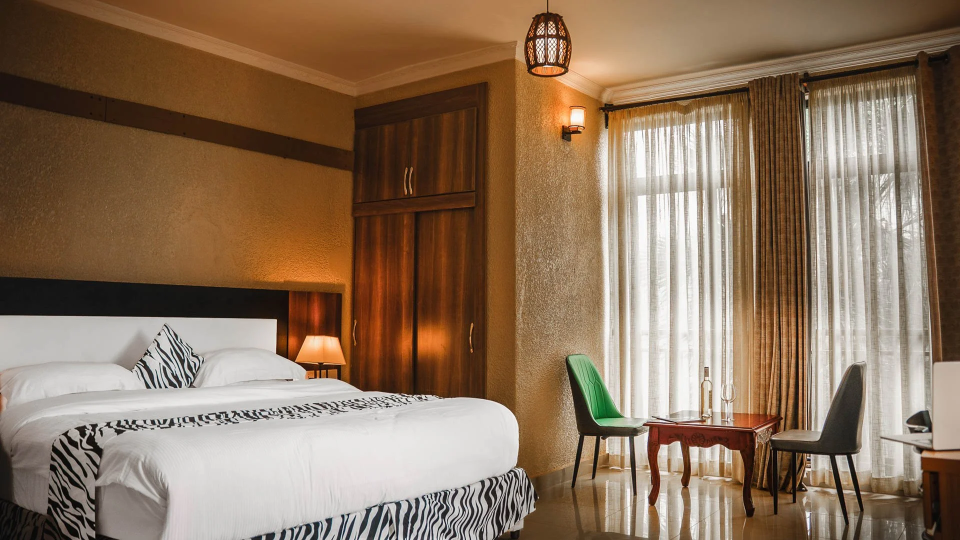 Quiet, comfortable, and spacious hotel room at Quality Inn Hotel Kigali in Rwanda with white bedding, zebra print accents, a seating area, and large windows—ideal for couples, families, and business travelers