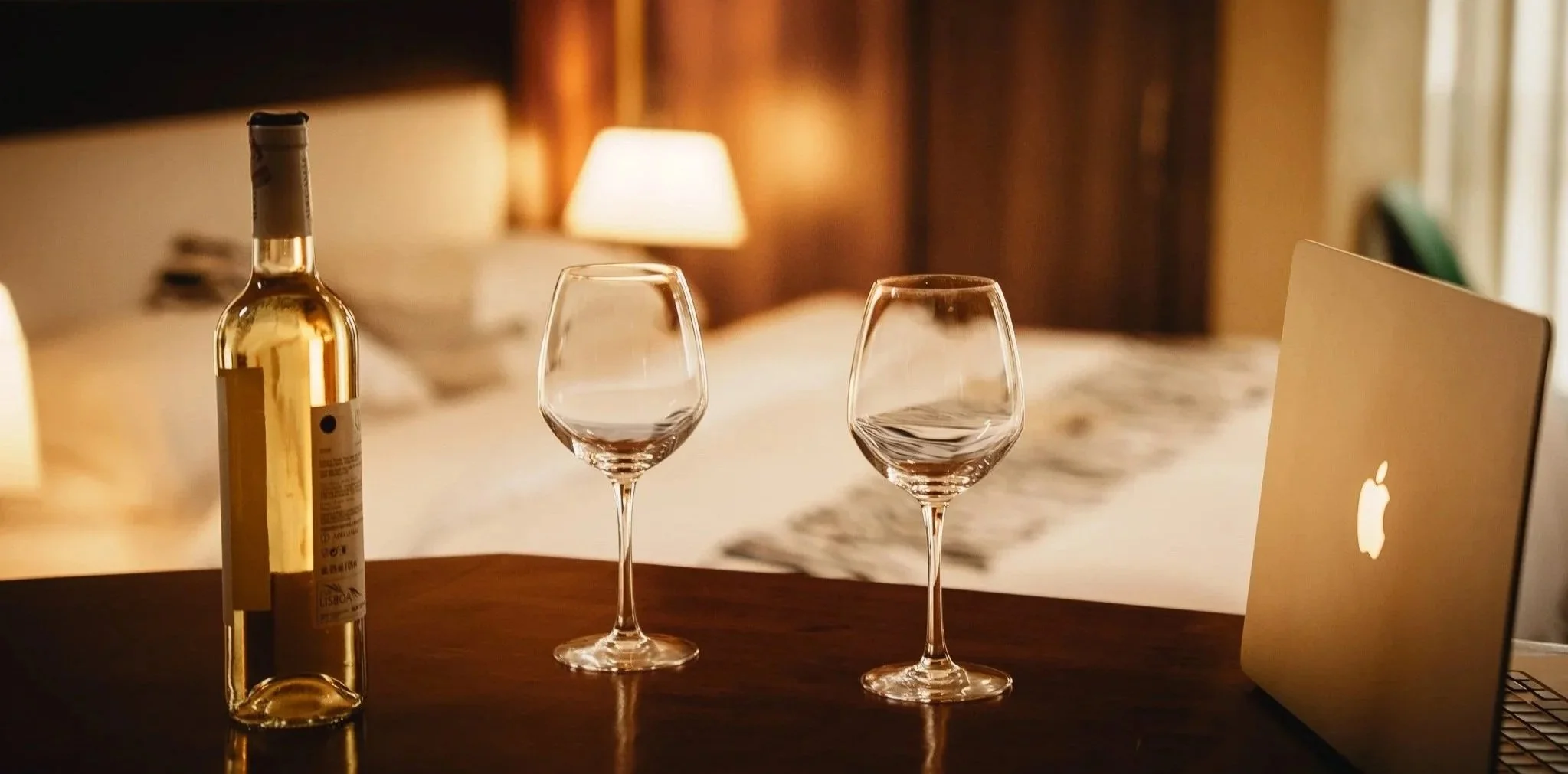 Quiet hotel room hideout with a bottle of white wine, two wine glasses, and laptop on wooden table, cozy setting for relaxing evenings at Quality Inn Hotel Kigali, Rwanda