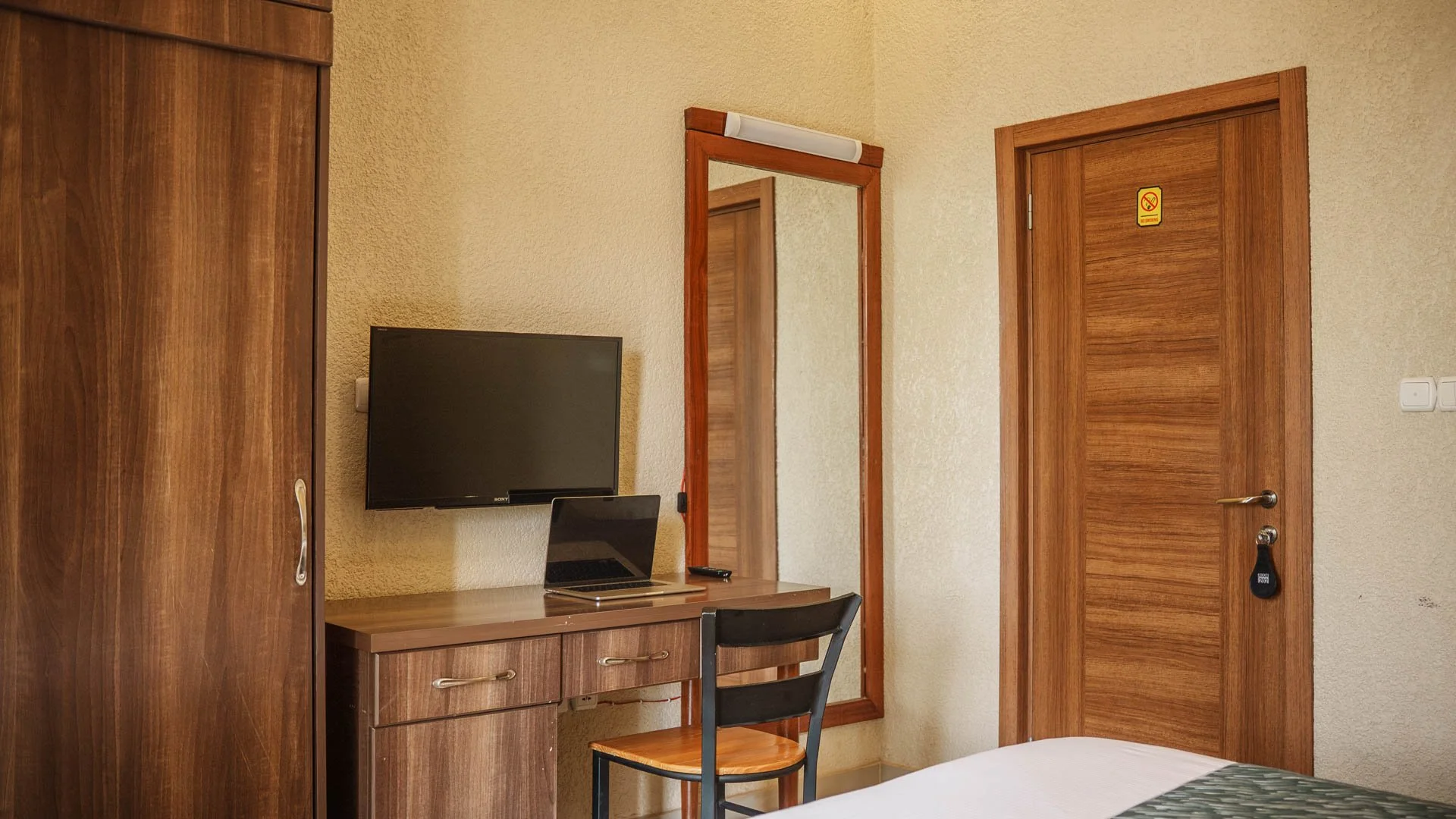 Quiet room with wooden furniture, wardrobe, wall-mounted TV, mirror, desk, chair at Quality Inn Hotel Kigali, Rwanda