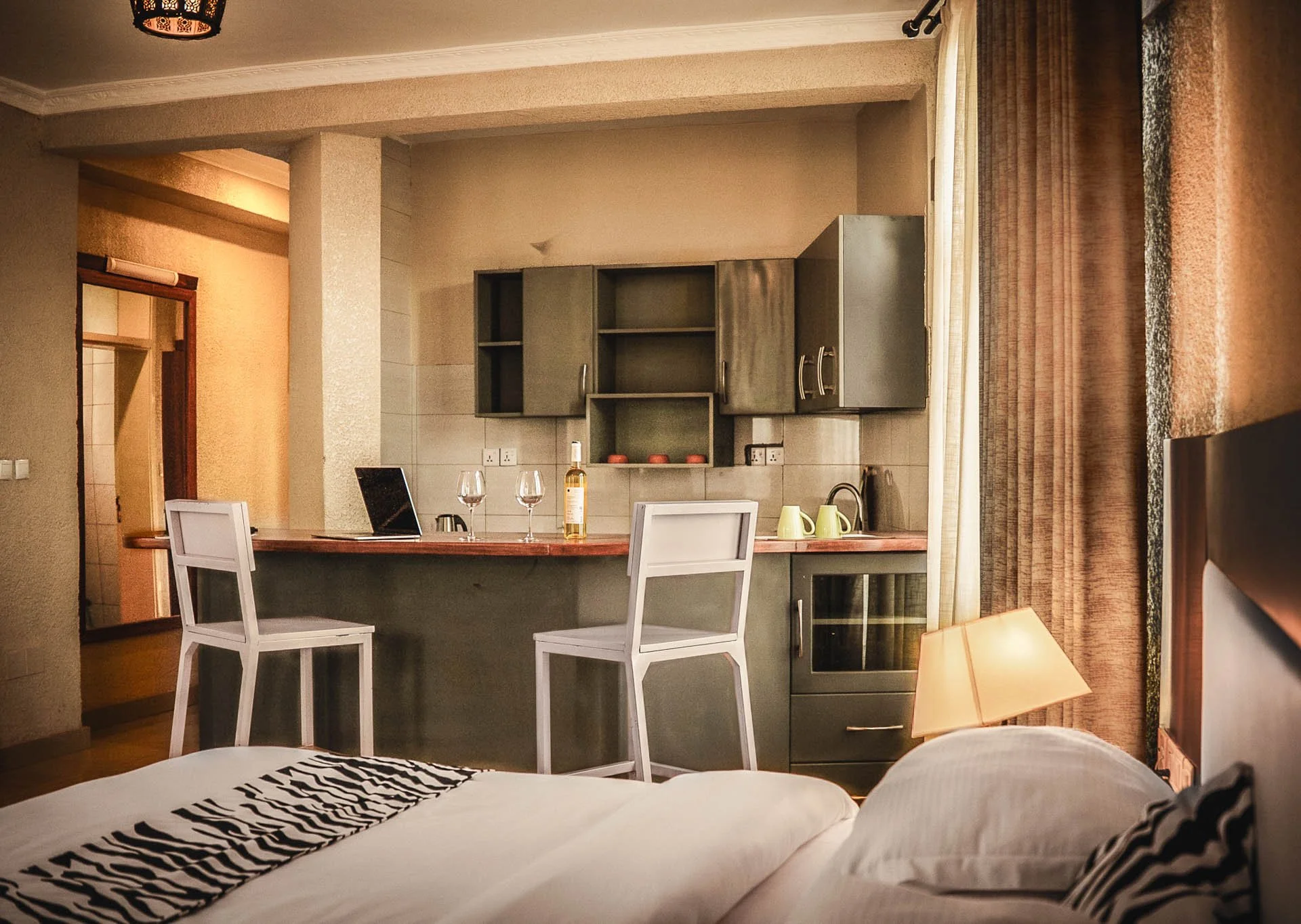 King Studio at Quality Inn Hotel Kigali, Rwanda: cozy super king bed, zebra-print runner, kitchenette, bar with wine & stools—perfect for couples & friends traveling in Rwanda seeking a comfortable and stylish stay.