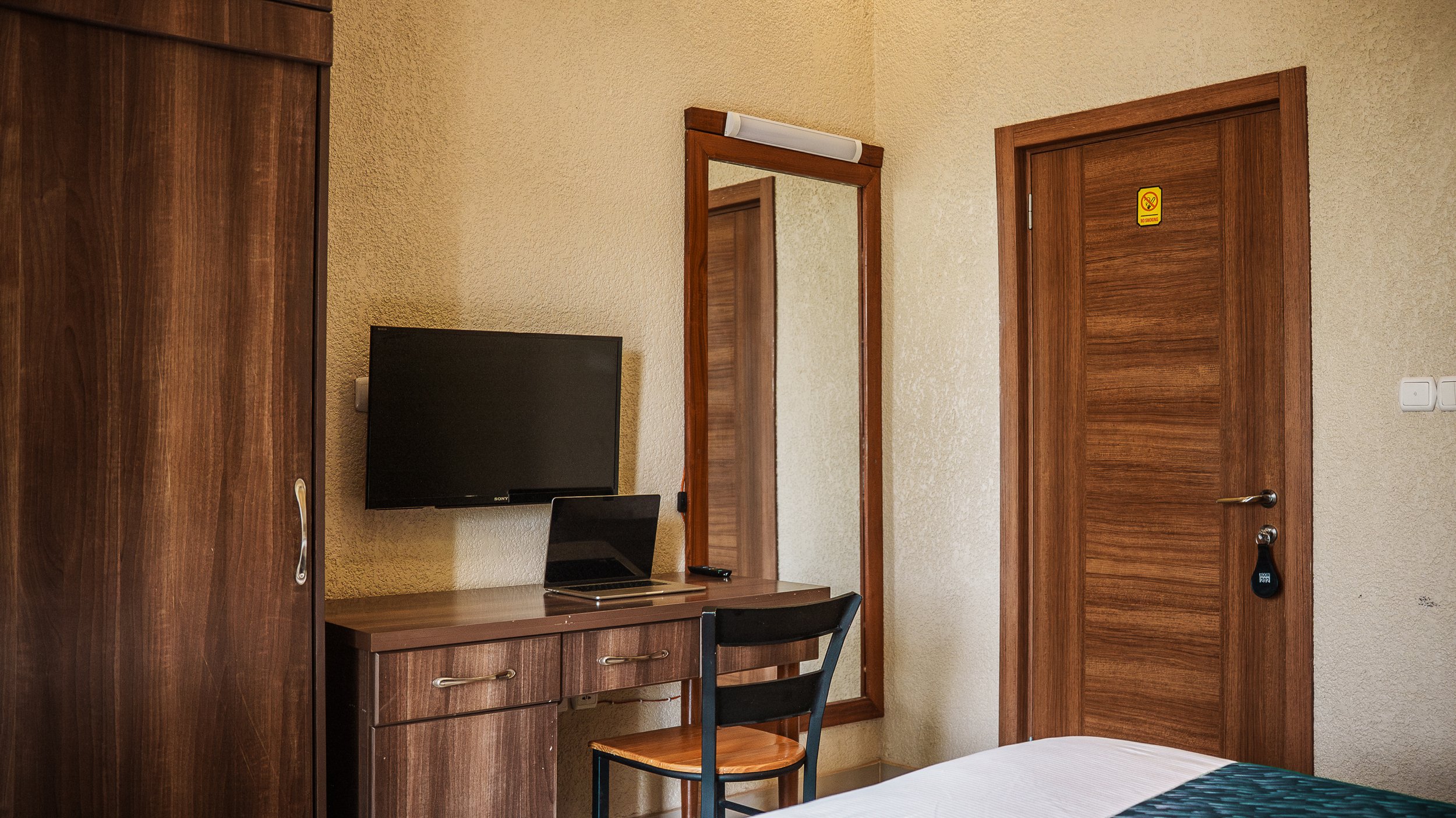 Quiet room with wooden furniture, wardrobe, wall-mounted TV, mirror, desk, chair at Quality Inn Hotel Kigali, Rwanda