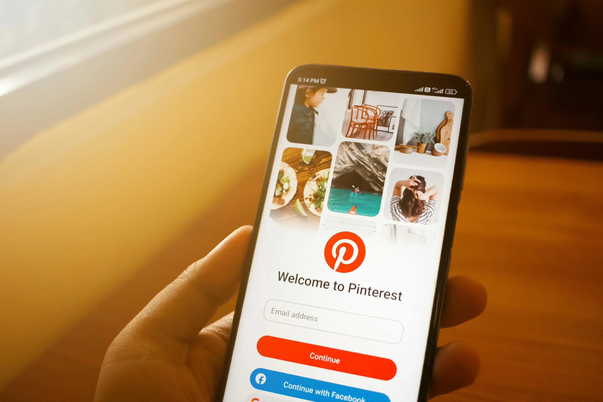 Person holding a smartphone with the Pinterest app login screen displayed.