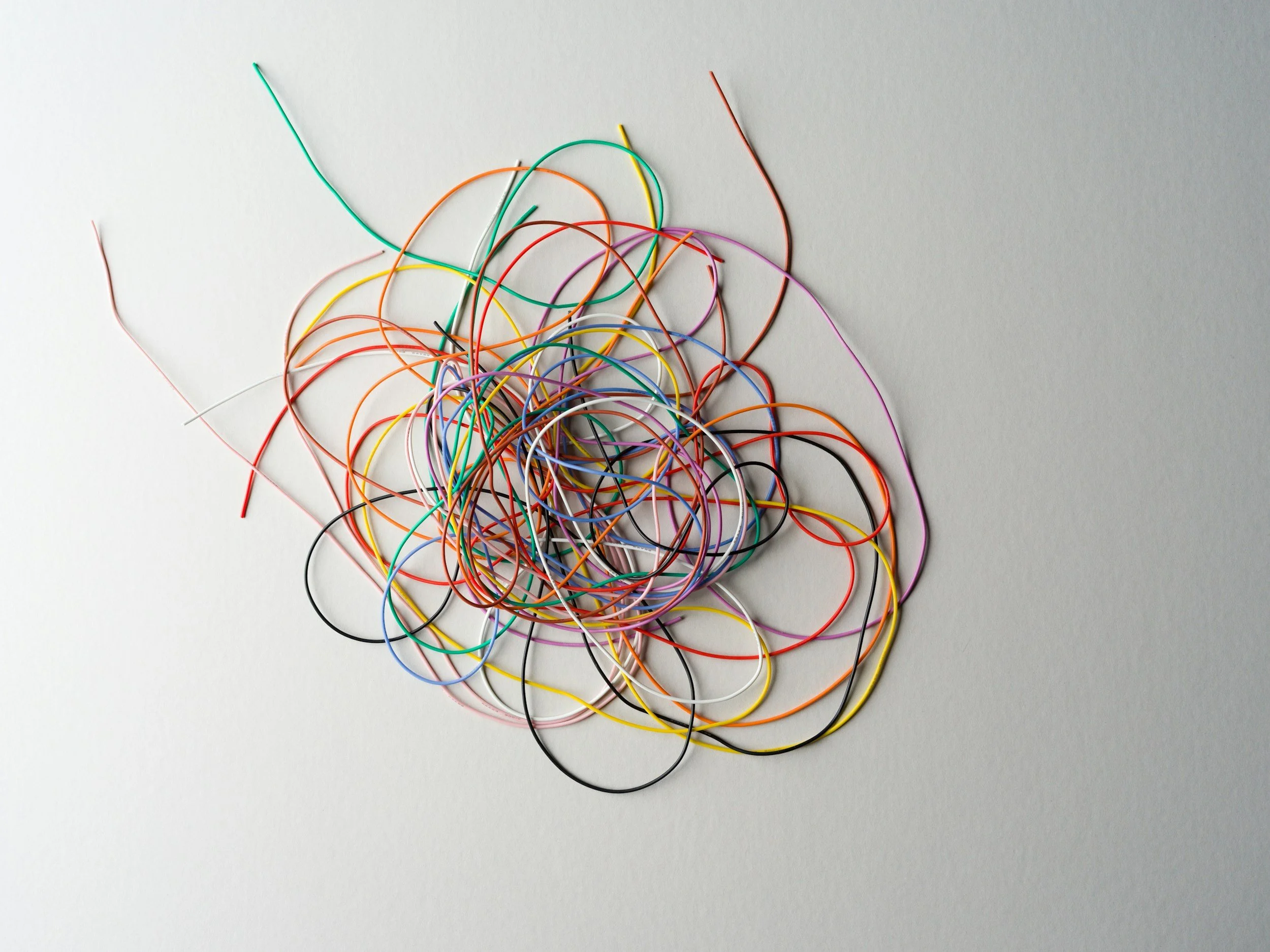 A pile of colorful rubber bands tangled on a white surface.