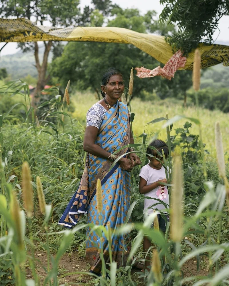 Suman, the widow of a farmer in Maharashtra, India standing with a child on the family farm.