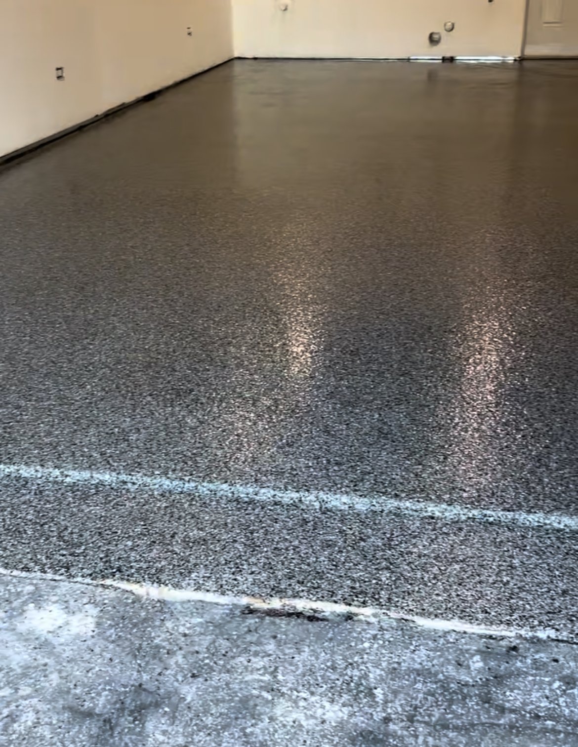 Newly poured epoxy floor with a black, speckled finish a room