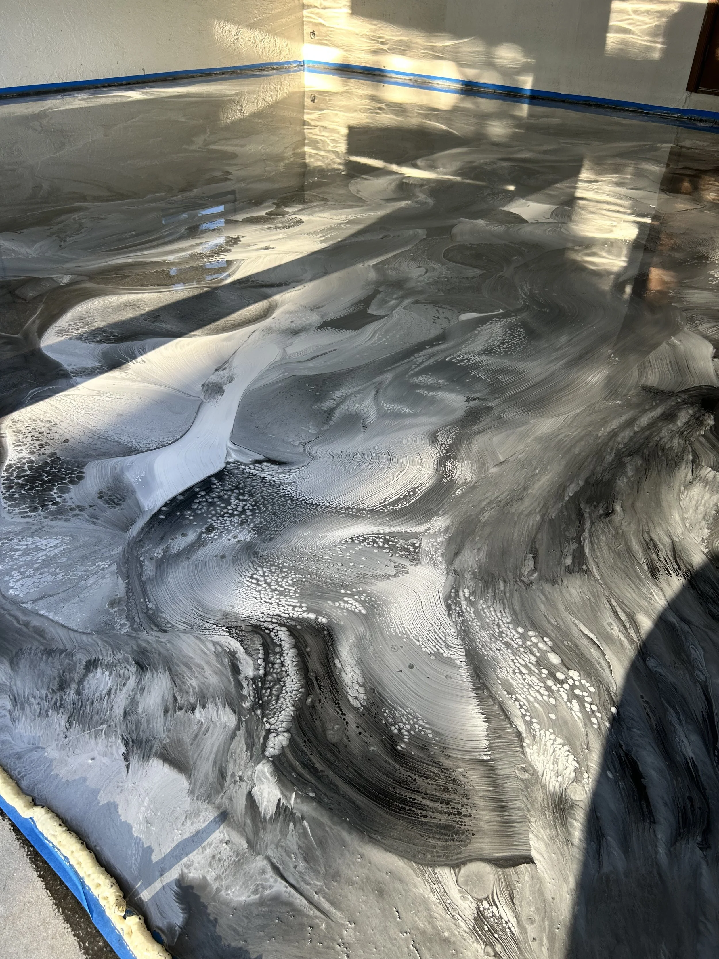 Drywall with epoxy coating and swirling finish in a room, with visible shadows and sunlight streaming in.