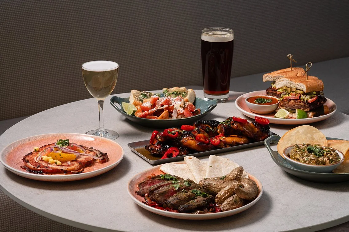 Variety of dishes including pork belly, ribs, mexican white shrimp, salad, and drinks on a table.