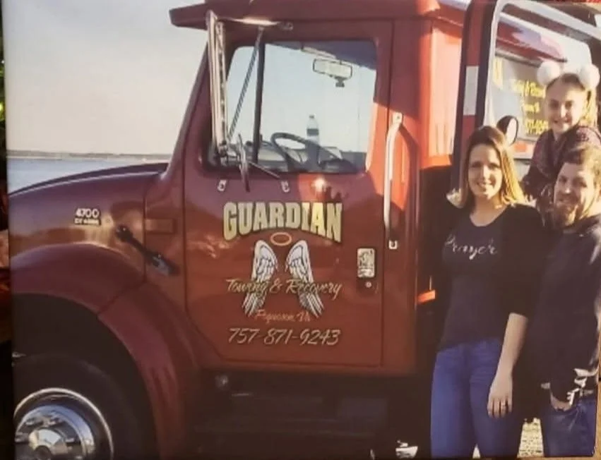 Three people standing next to a red Guardian church bus, with the church's logo and contact information on the door.