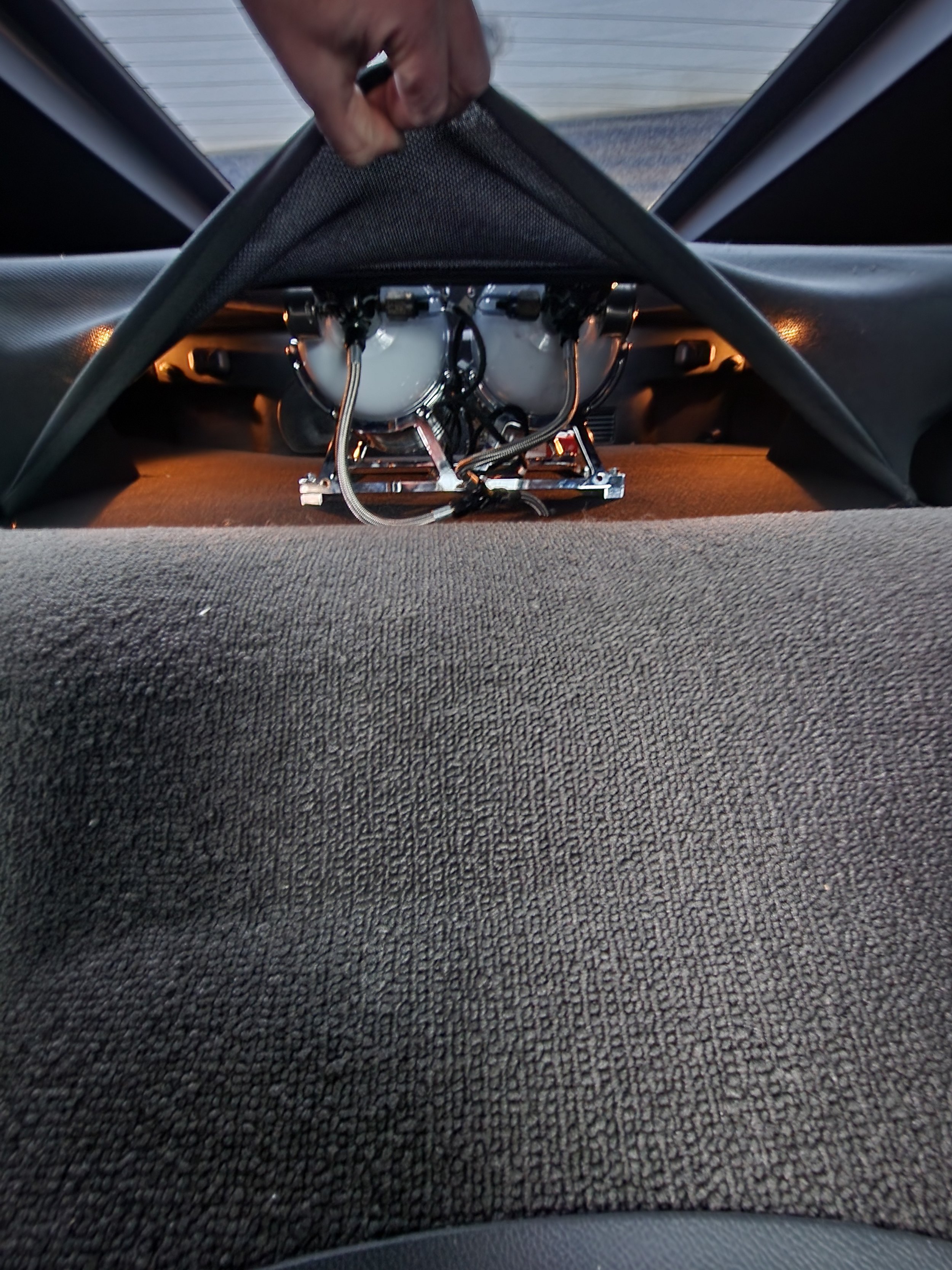 View from inside a vehicle showing the interior with a speaker system being installed, with wiring and components visible. The photo is taken from the backseat looking toward the front.