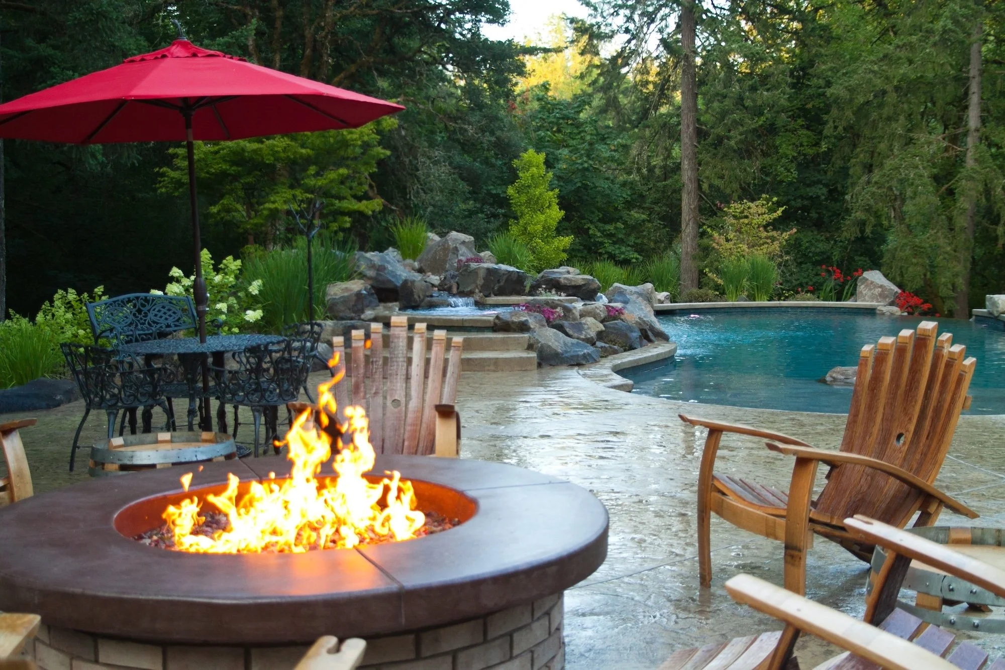 Fire pit with stamped concrete patio, stone waterfall, and inground pool