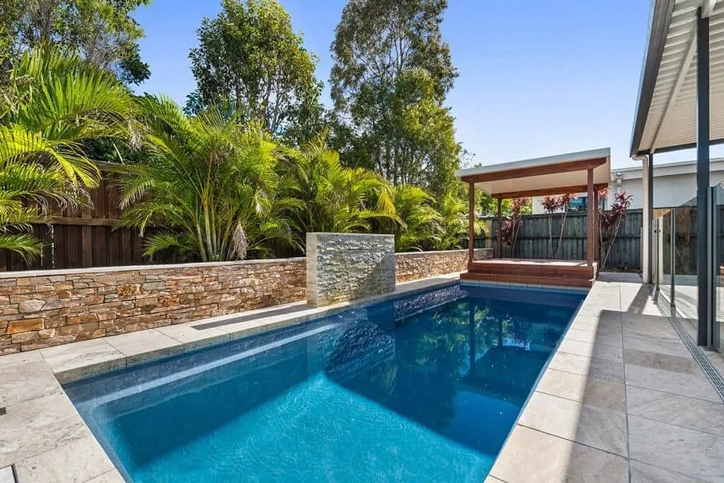 Inground pool with retaining wall and sleek waterfall