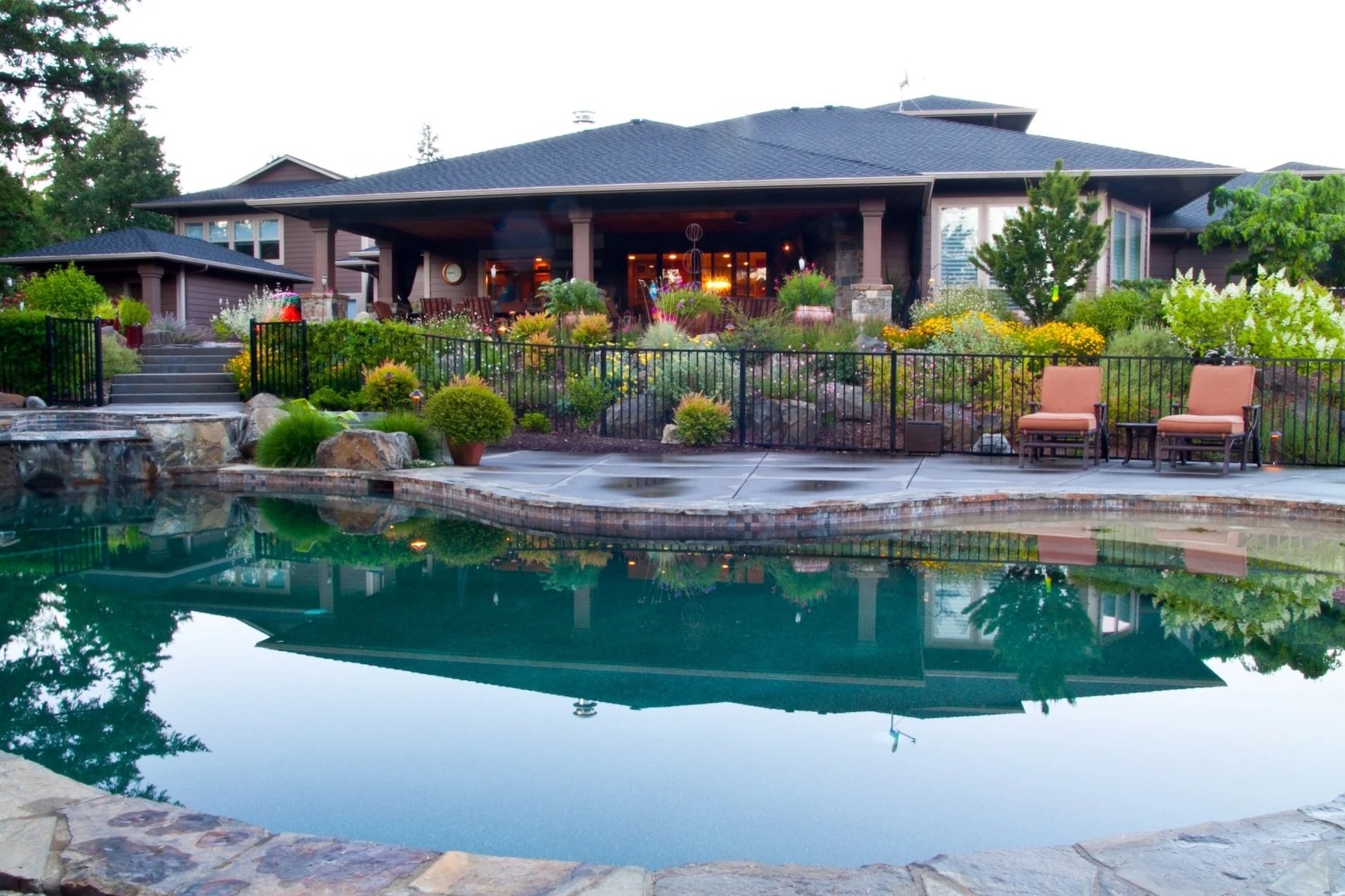 Inground pool with lush green plantings and black aluminum fencing