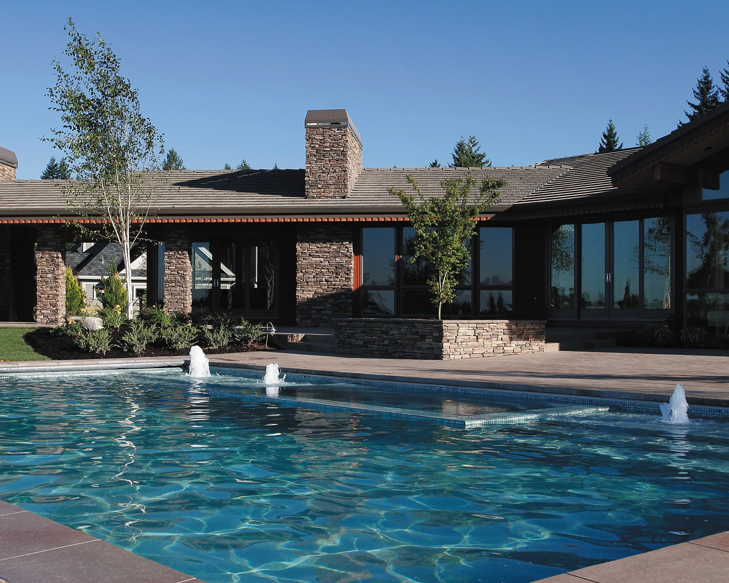 Inground pool with integrated spa and water features