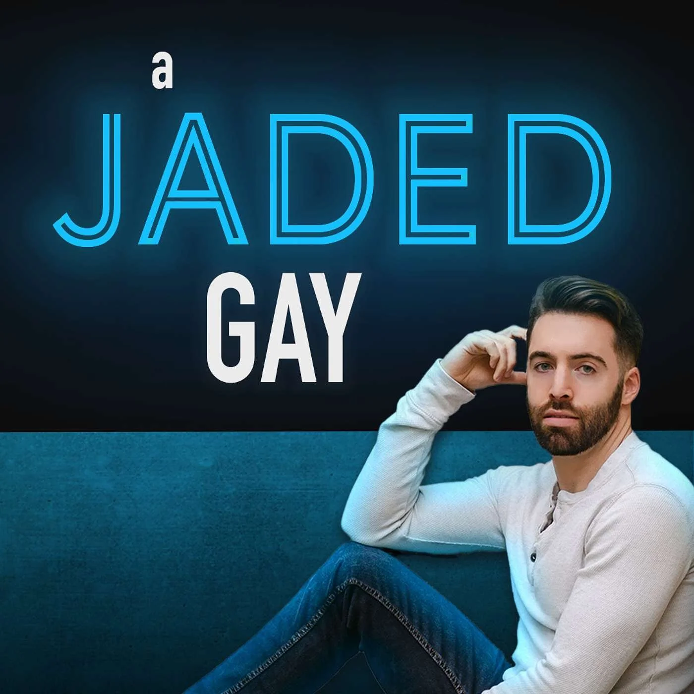 A man with a beard and short dark hair, wearing a white long sleeve shirt, sitting on a teal couch with one arm resting on the back, looking directly at the camera. Behind him, a dark background features the words "a Jaded GAY" in large, blue neon-style letters.