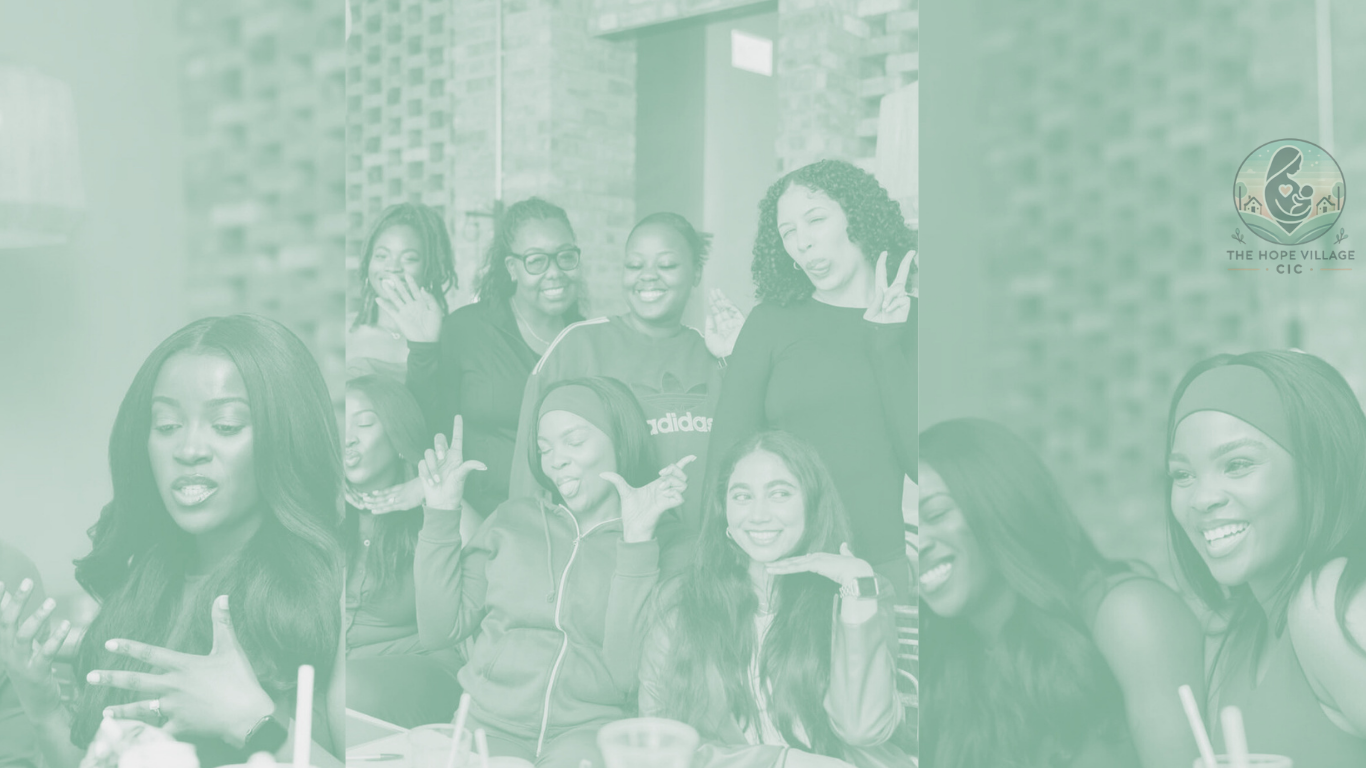 Group of women smiling and posing together indoors, some making gestures, with a logo in the top right corner that says 'The Hope Village CIC'.