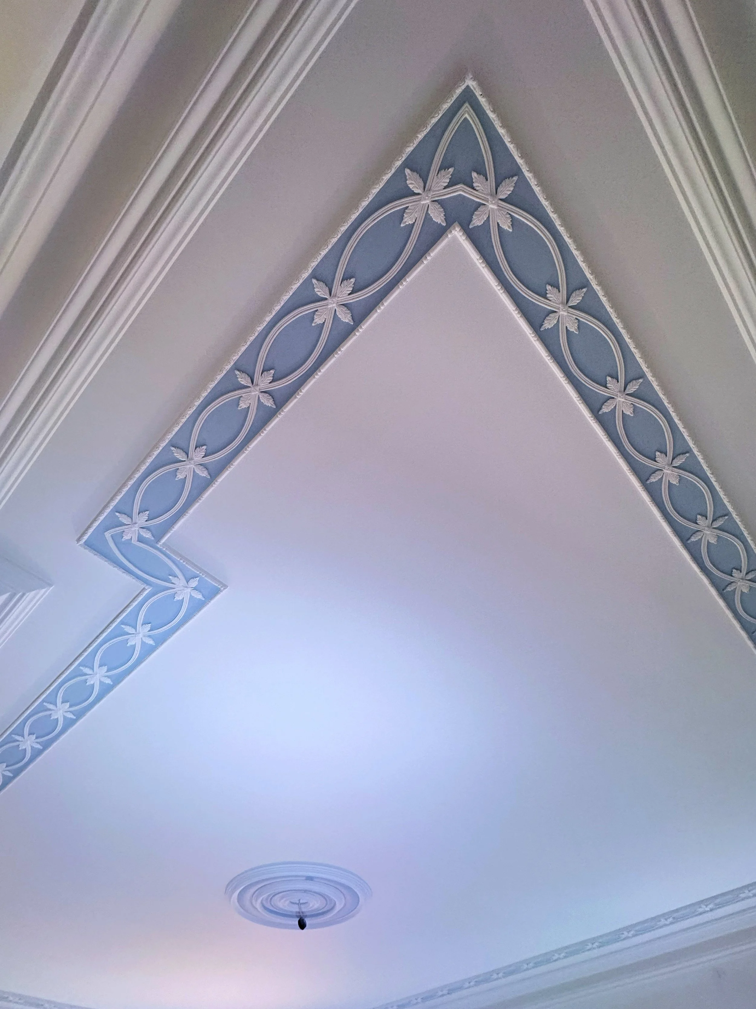 Ceiling with decorative blue border featuring white floral and circular patterns.