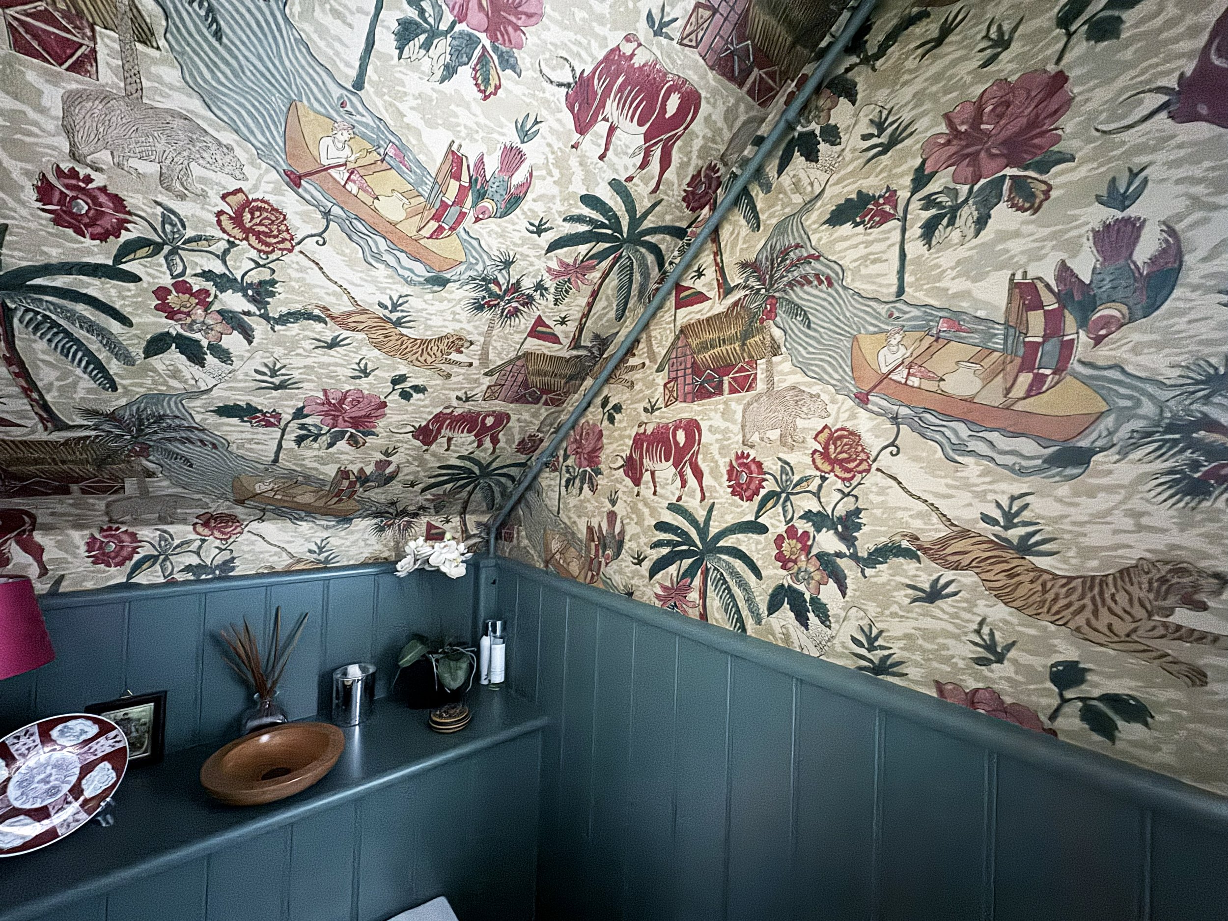 Decorative wall with tropical and jungle themed mural, featuring animals like tigers, lions, crocodiles, and birds, as well as palm trees, flowers, and people in boats.