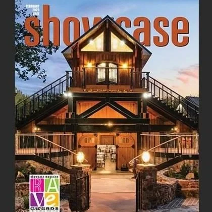 A rustic two-story barn-style building with outdoor staircase railings, lit up at dusk, with the word 'Showcase' in large orange letters at the top and a 'RAVE' awards logo at the bottom left.