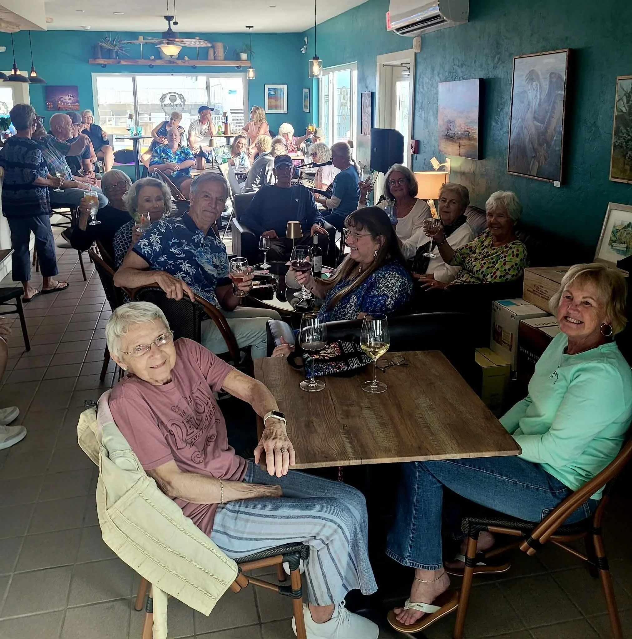 Group of elderly people sitting at a wine bar enjoying drinks and conversation.