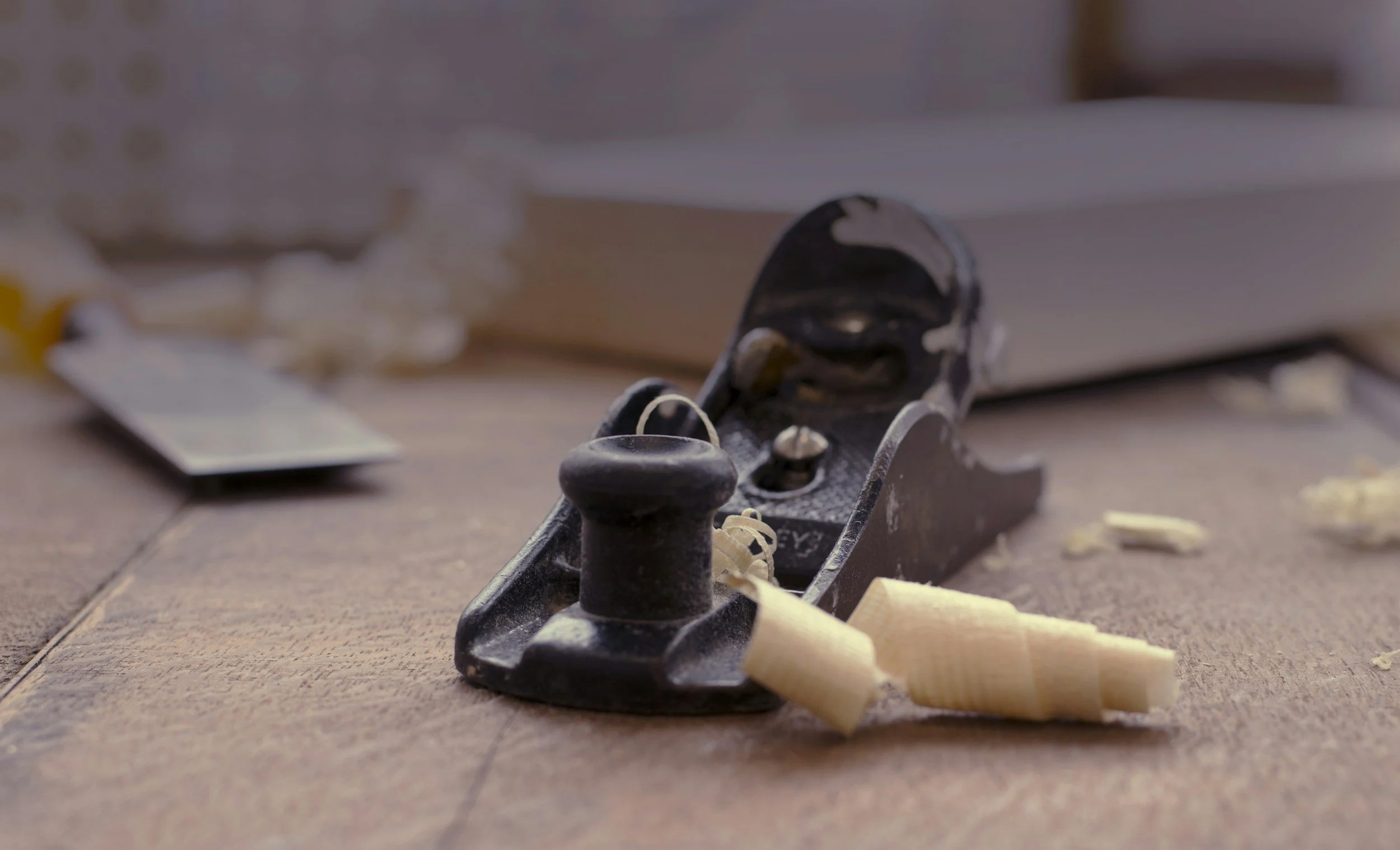 Close-up of a carpenter's hand plane and wood shavings on a wooden workbench.