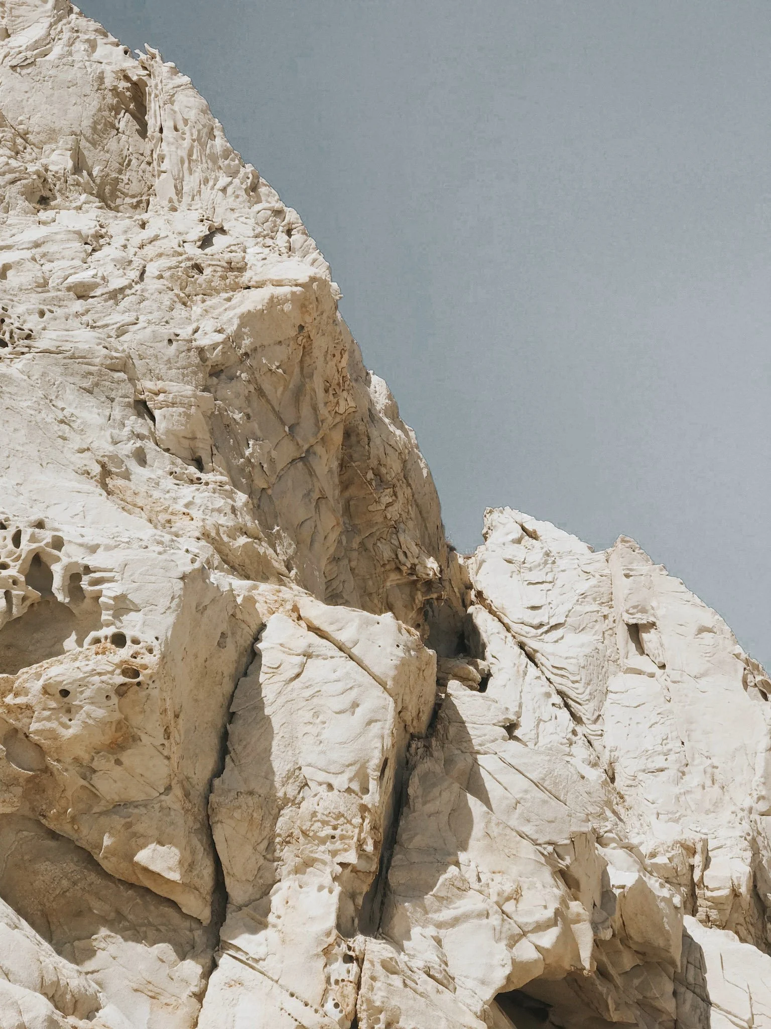 Close-up of rugged white limestone cliffs beneath a clear blue sky