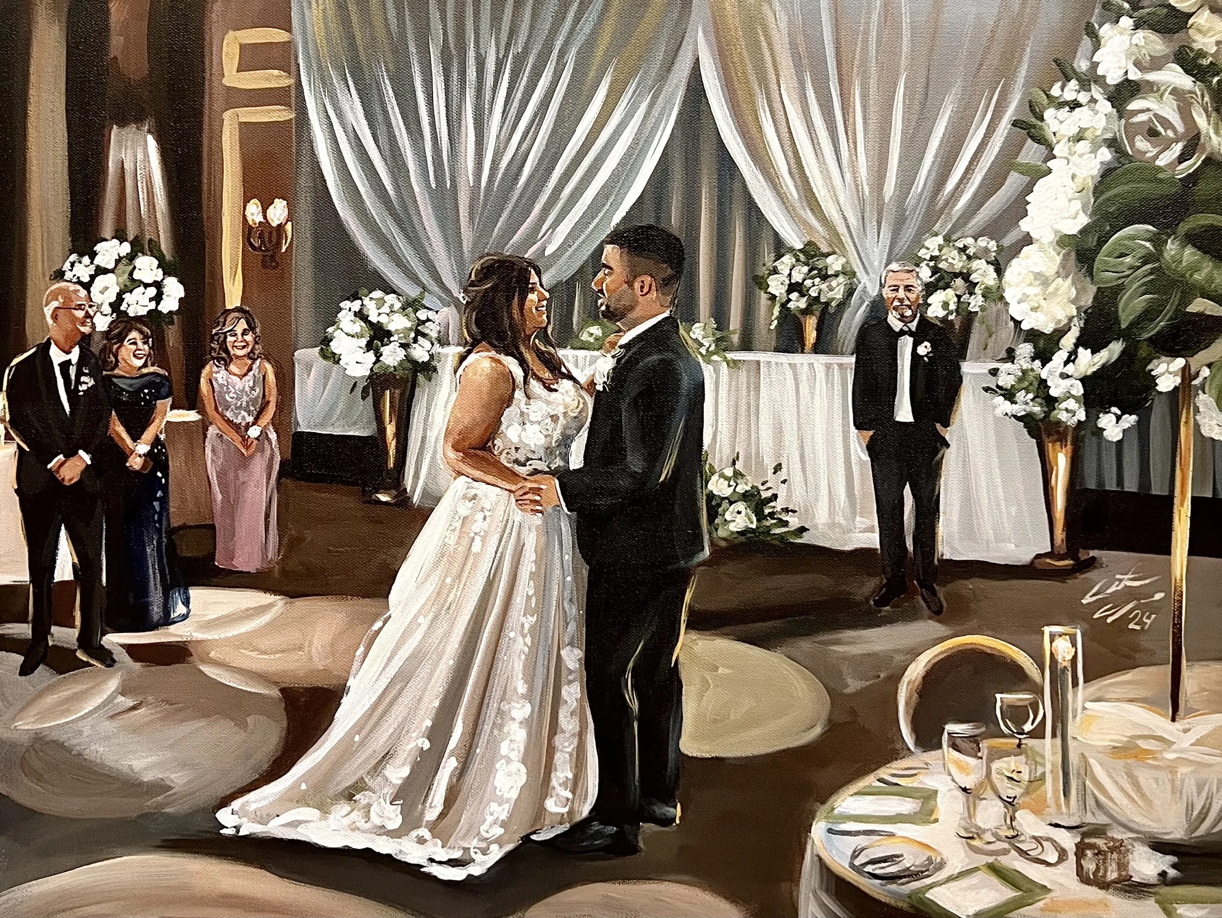 A wedding reception scene with a bride and groom holding hands and facing each other in the center, surrounded by guests in formal attire. The background features large white floral arrangements, draped curtains, and a decorated table with a white ta