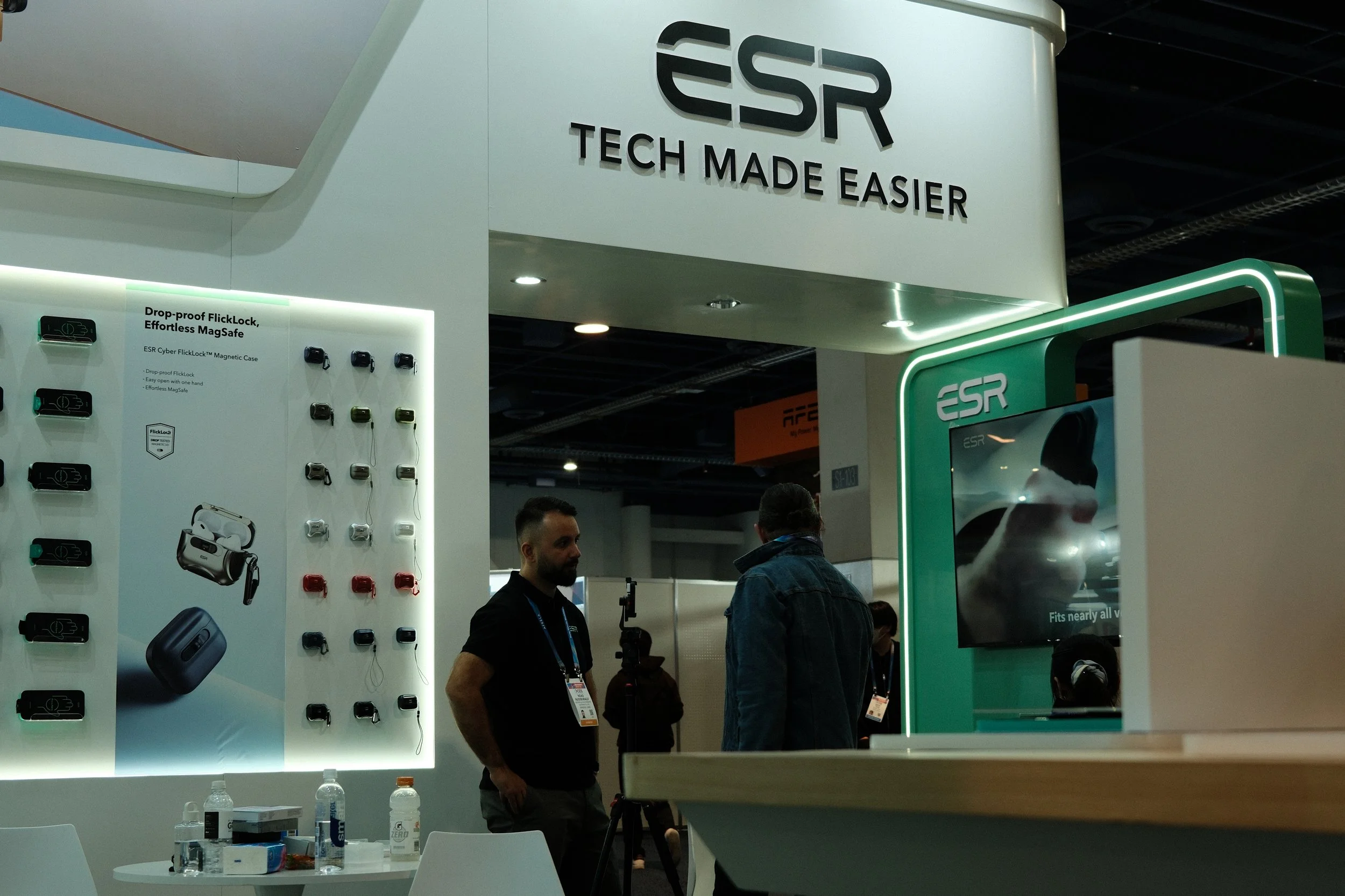 Trade show booth for ESR featuring displays of tech accessories like magnetic cases, earphones, and chargers with the slogan 'Tech Made Easier'.