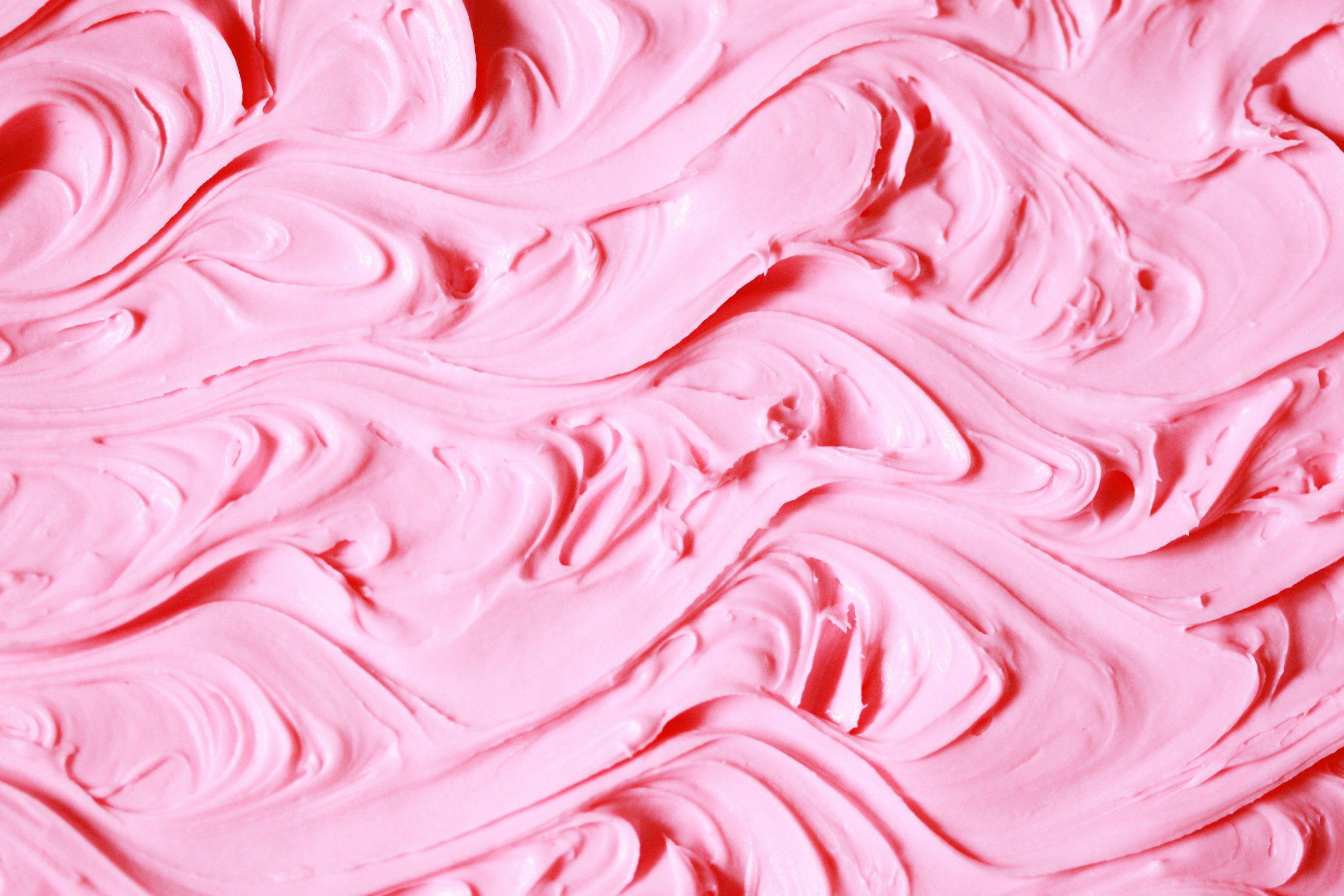 Close-up view of pink, swirled frosting with a creamy texture.