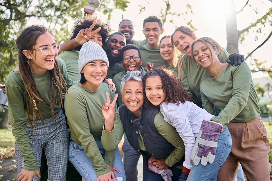 Group of diverse young people smiling and showing excitement outdoors in a park.