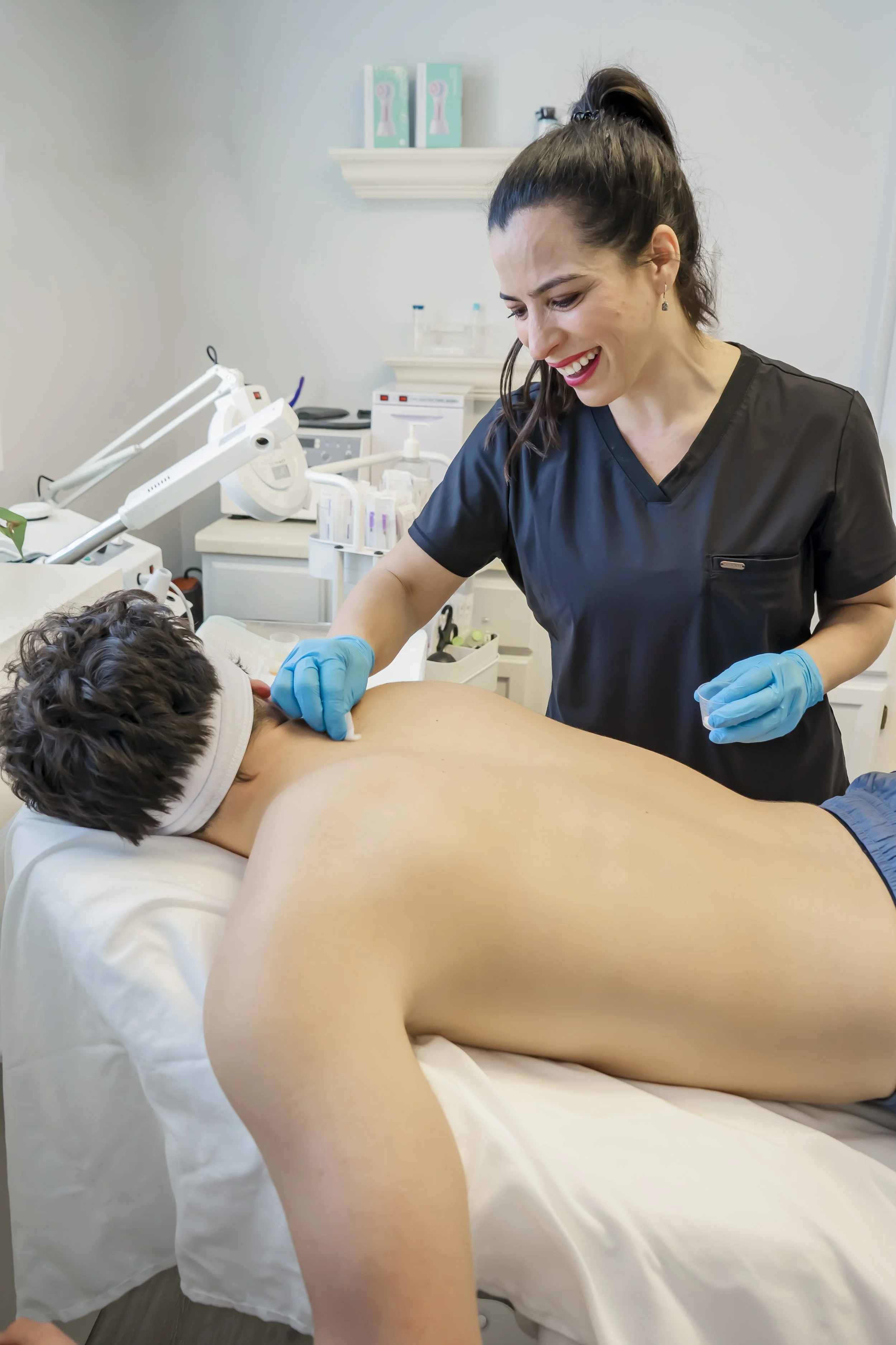Nurse practitioner Carla performing a chemical peel on a teen male client’s back at Carla Thomas Med Spa in La Grange, IL.