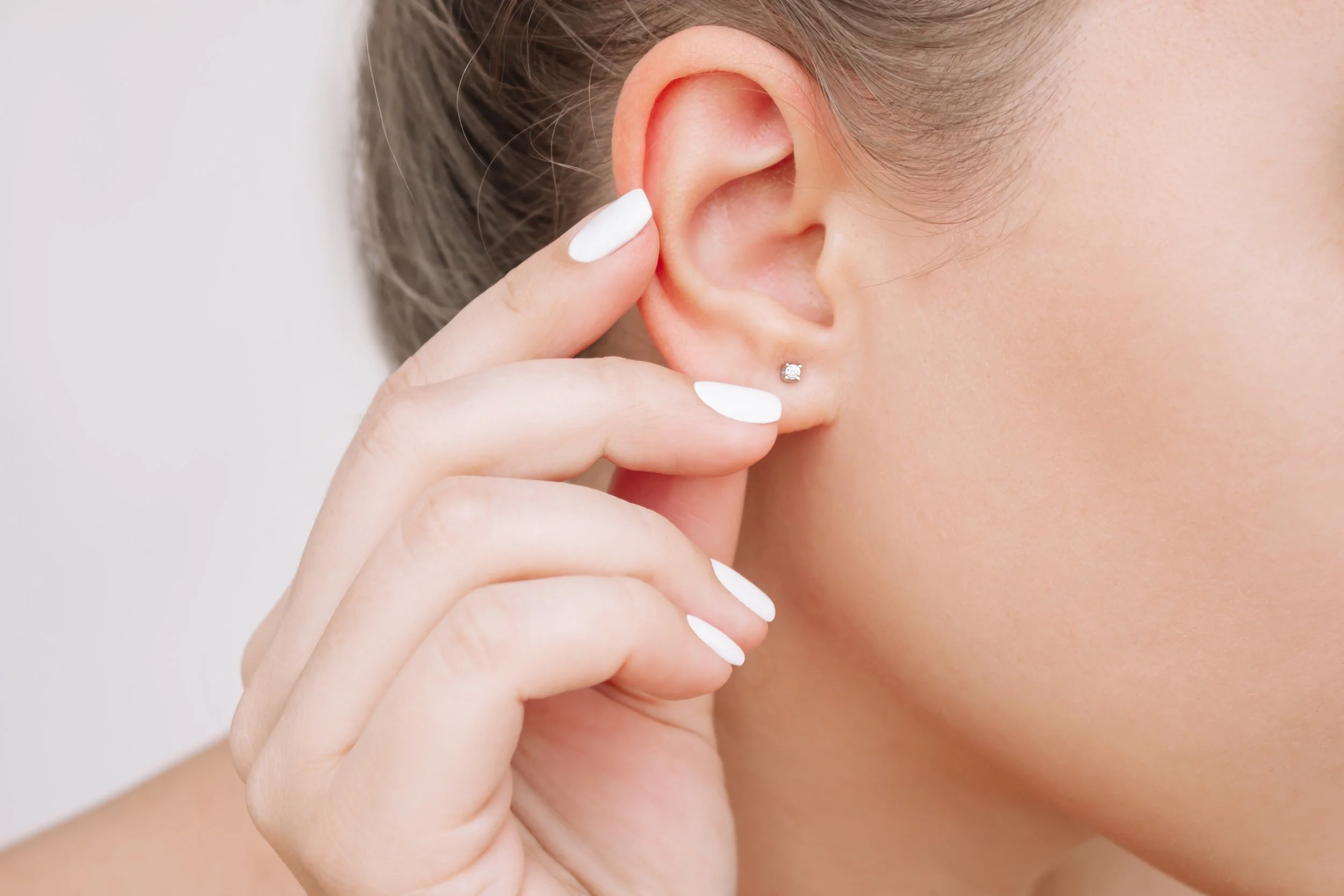 Close-up of a woman's earlobe with a diamond stud earring after professional ear piercing in La Grange, IL.