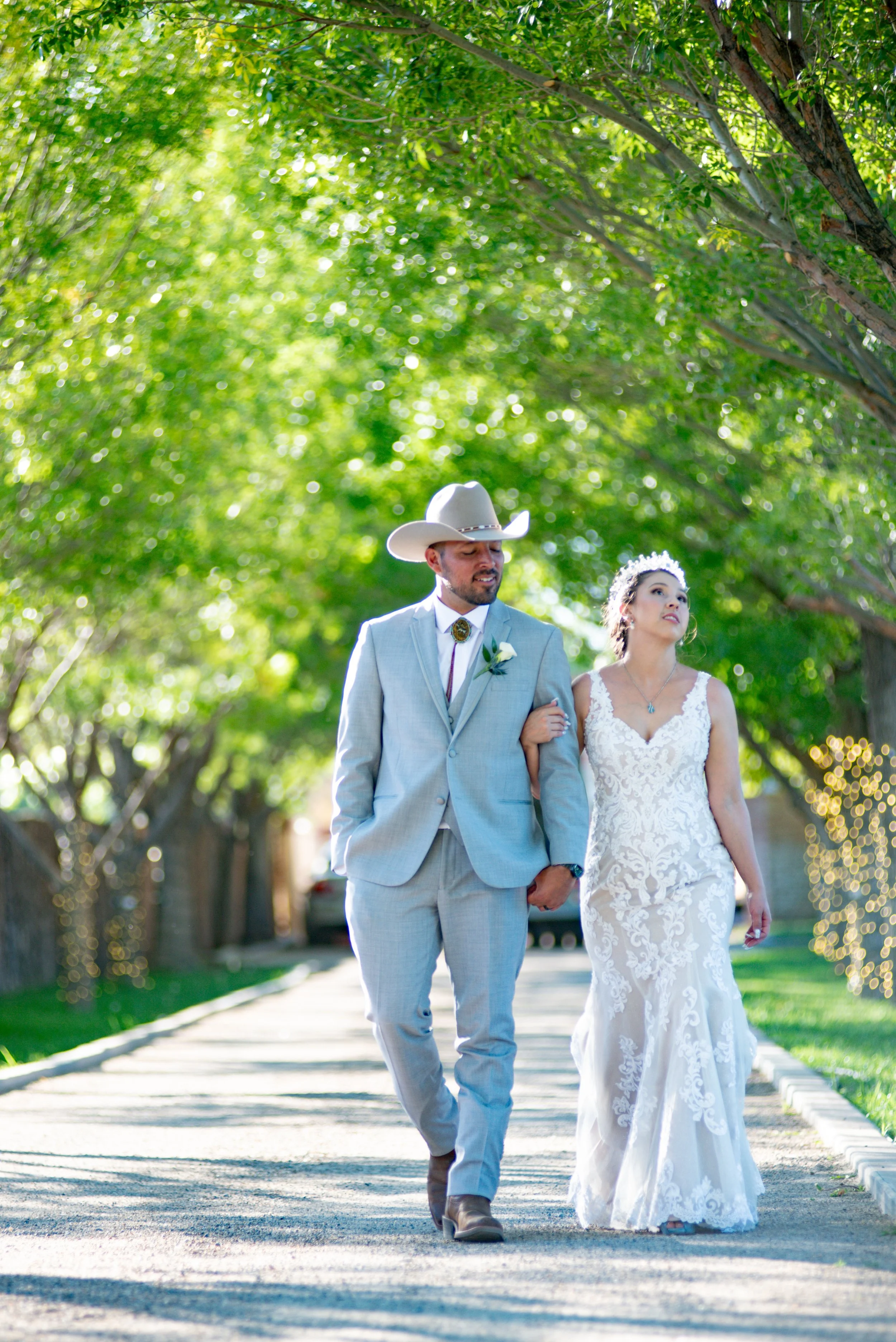 Bride and groom walking beneath trees after their Bernalillo New Mexico wedding ceremony