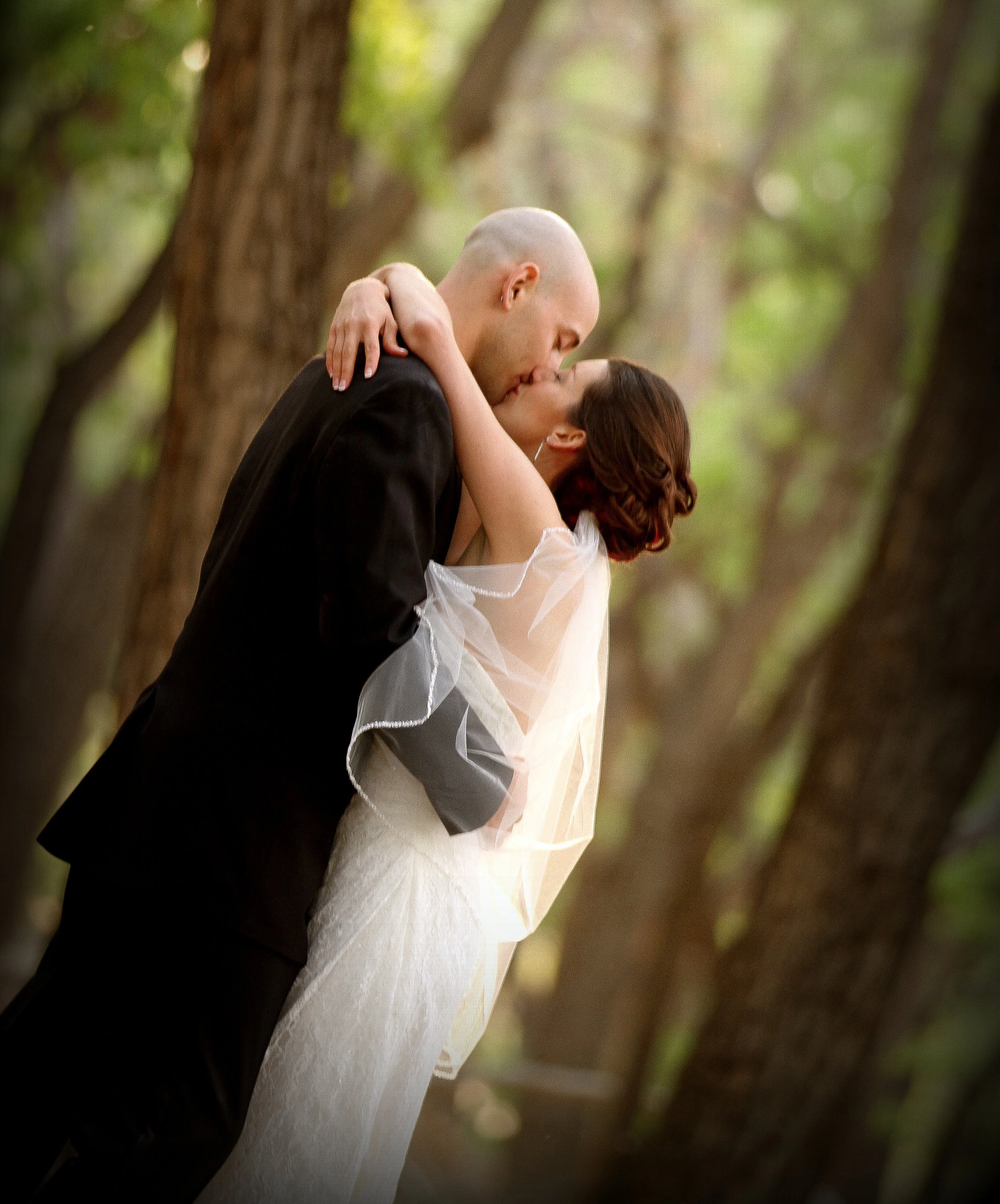 Tamaya Resort in Albuquerque - A bride and groom sharing a kiss in a forest with trees in the background.