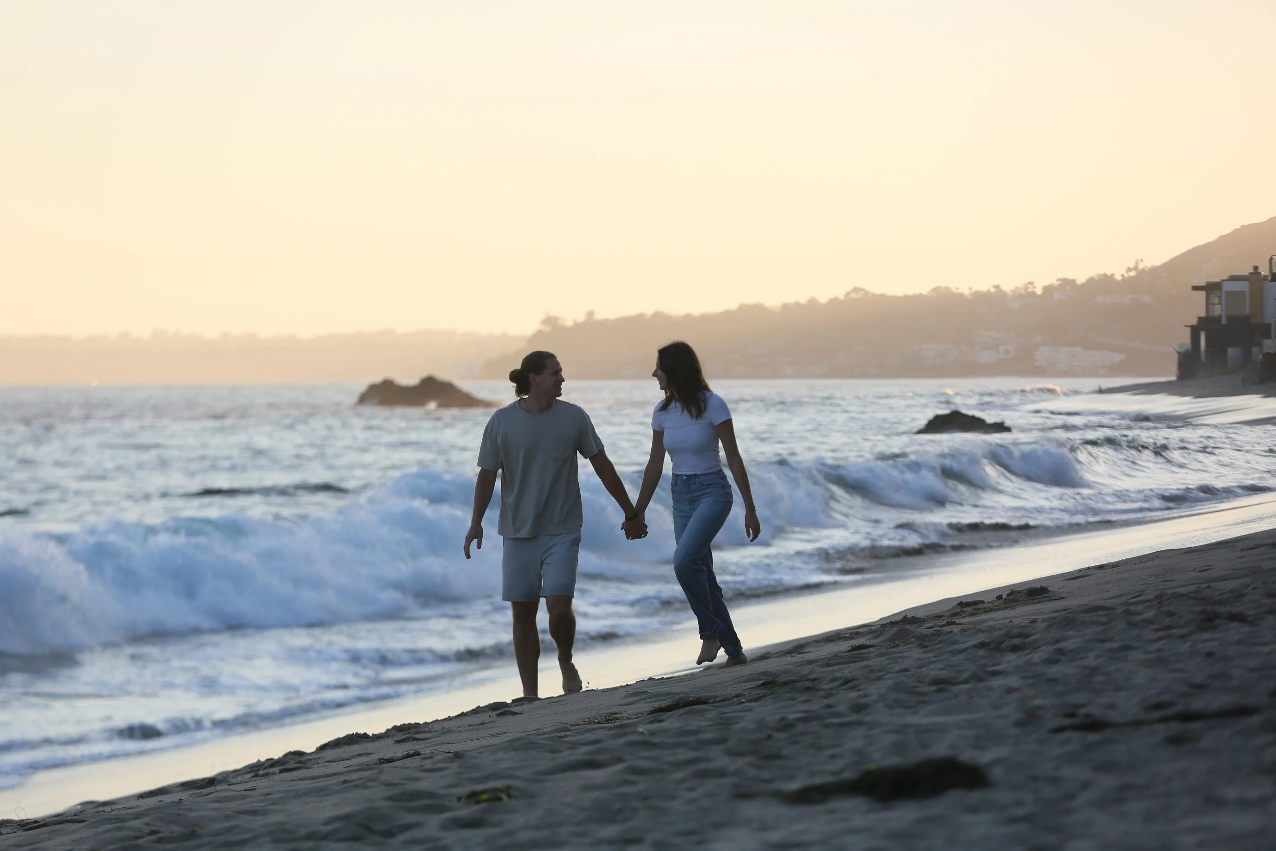 Engaged couple walking along the beach during a sunset engagement session at Point Doom in Malibu California