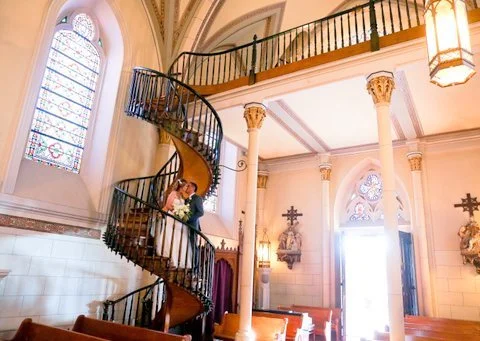 Bride and groom on a spiral staircase inside the historic Loretto Chapel in Santa Fe, New Mexico