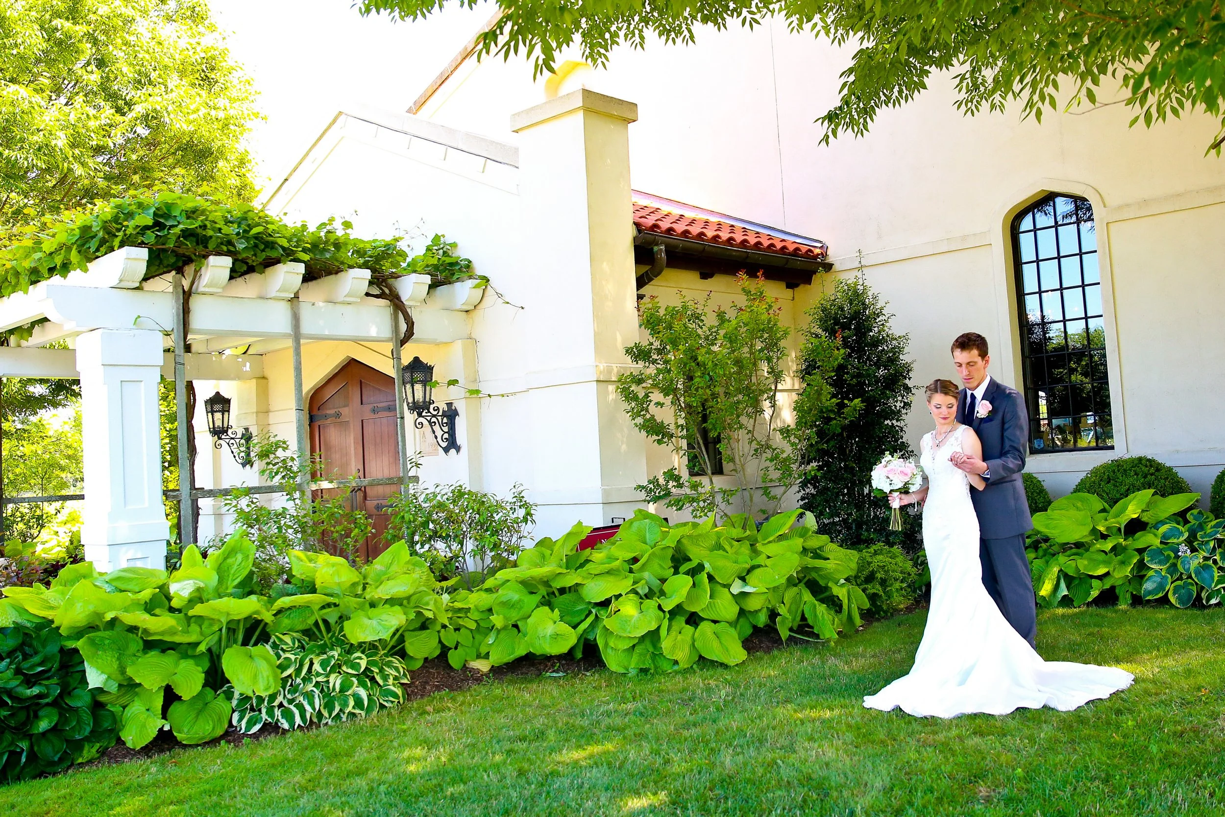 Bride and groom posing in a garden outside their Long Island wedding venue